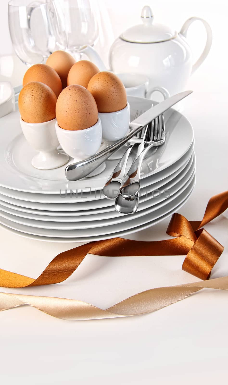 Brown eggs with plates for Easter breakfast on white