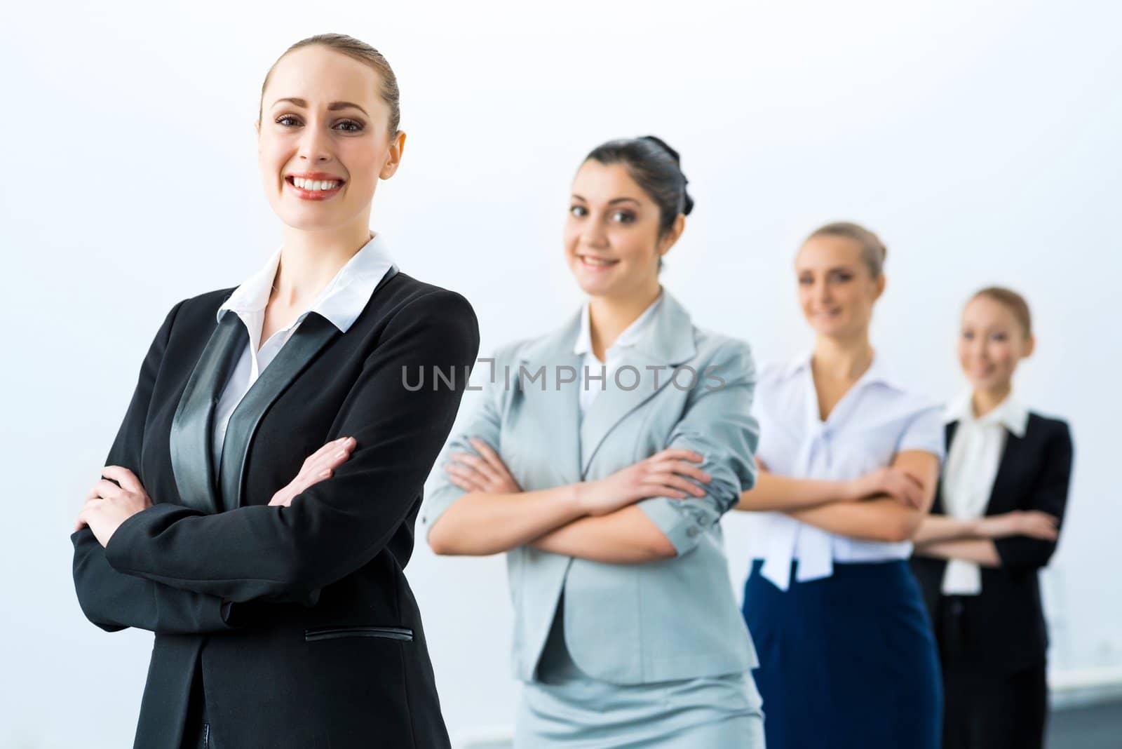 group of business people standing in a row, smiling and crossing his arms