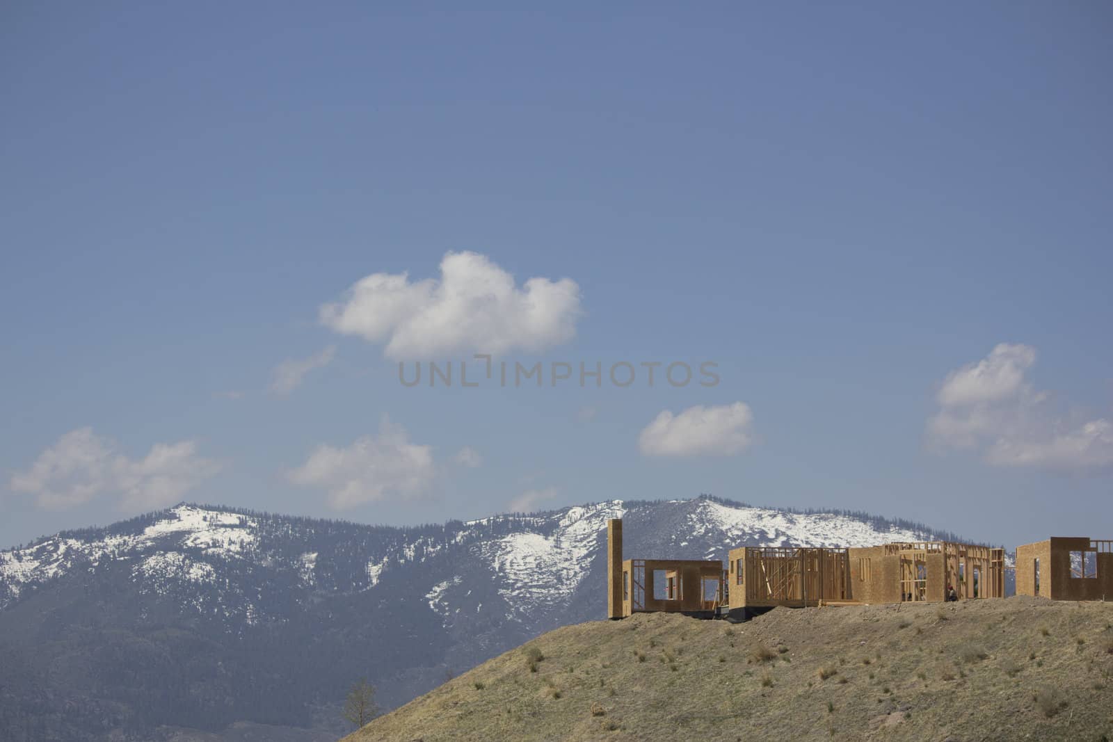 building a home on a ridge with the snowy mountains in the background