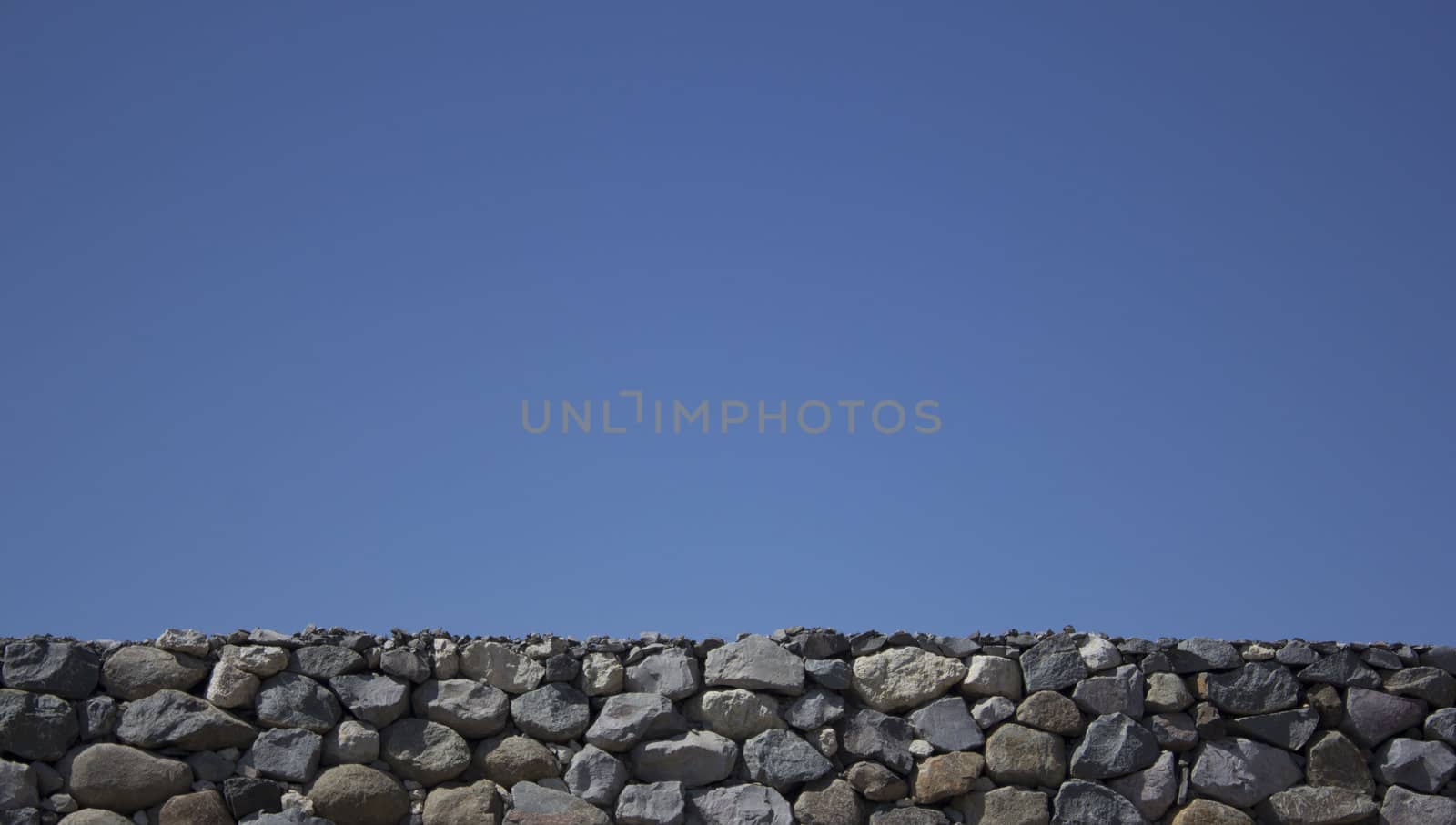 Rock boulder wall with a blue clear sky