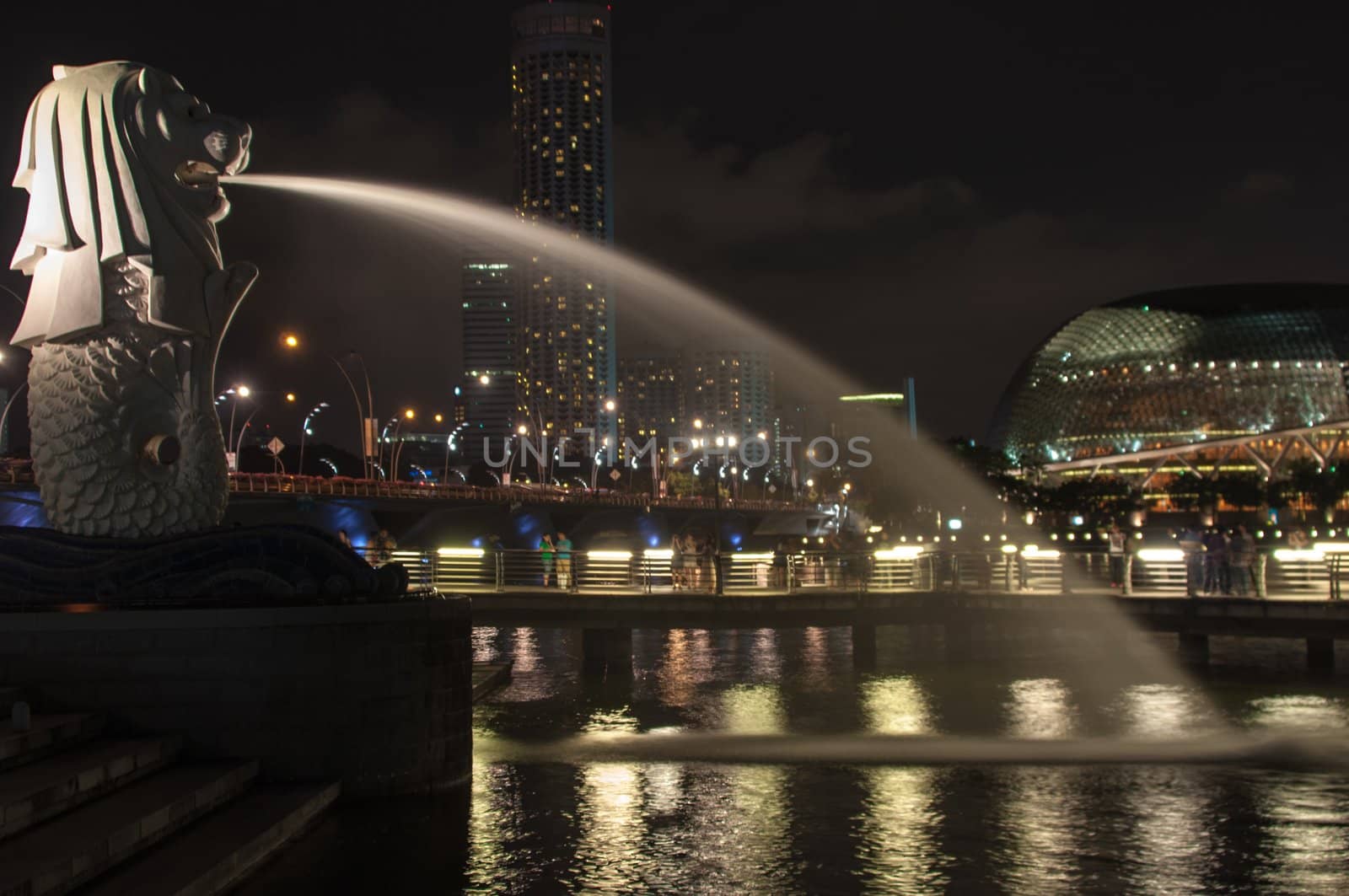 mythical symbol of Merlion in Singapore overlooking the city scape and esplanade at night