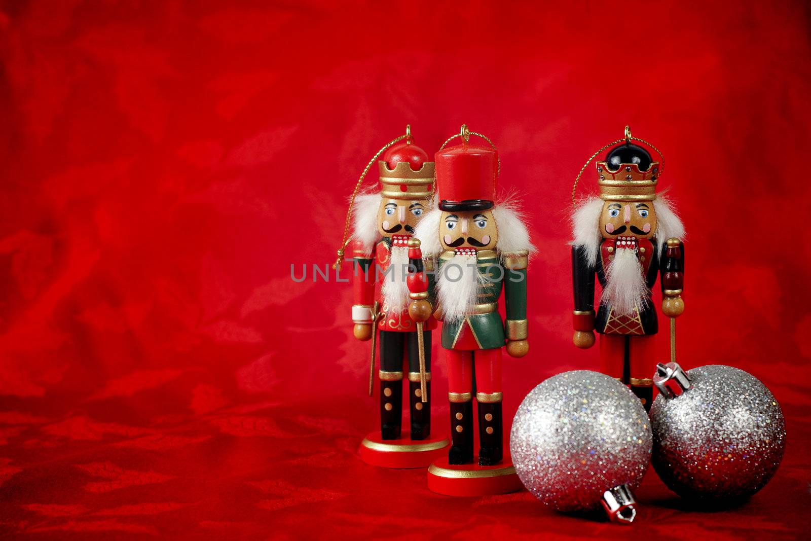 Three nutcrackers stand on red Christmas background with ornaments