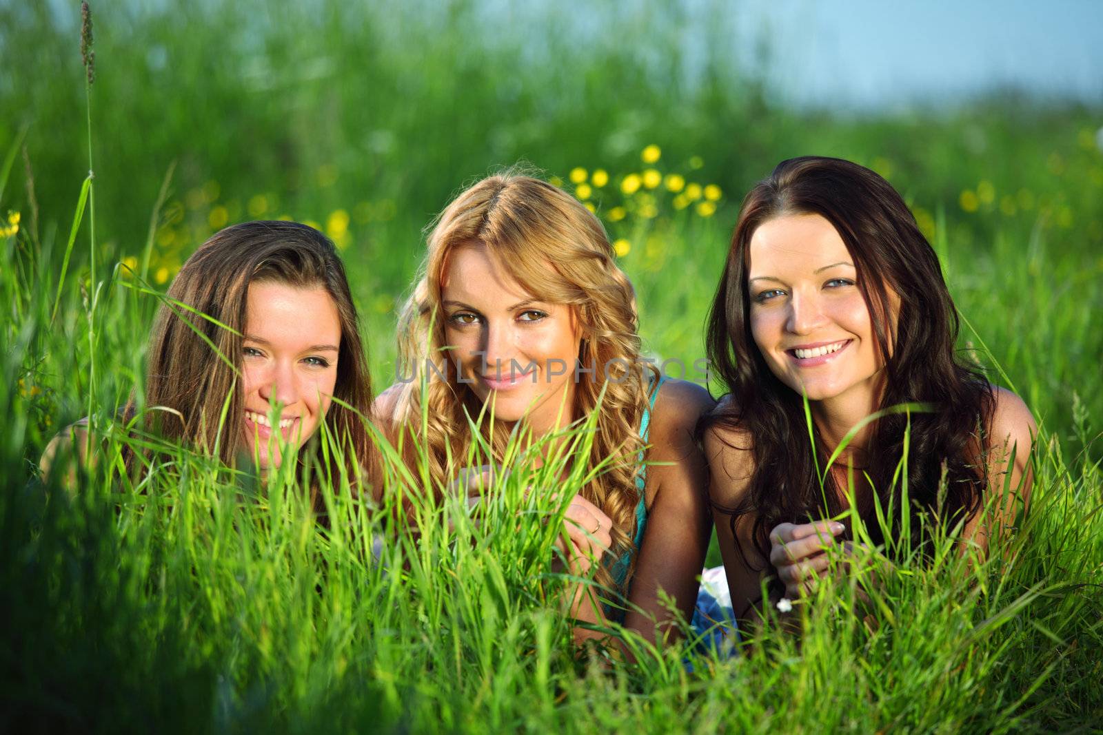 girlfriends lays on green grass and smile