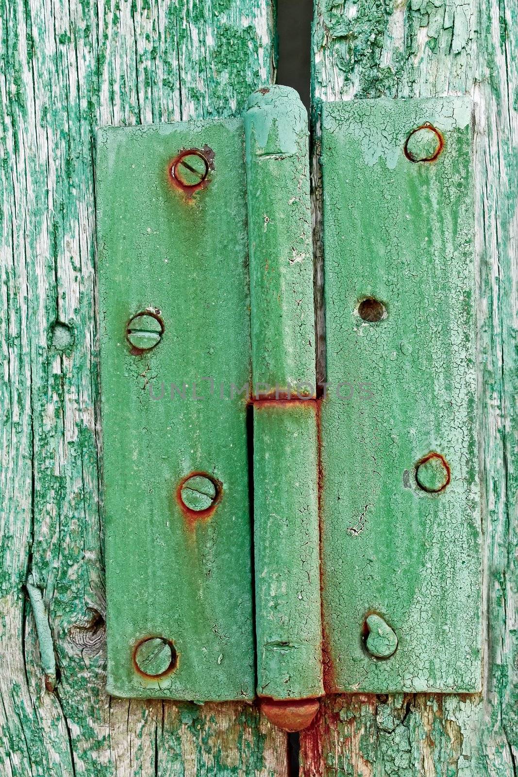 Old metal rusty hinges on the wooden boards covered with multilayered shelled with green and turquoise paint