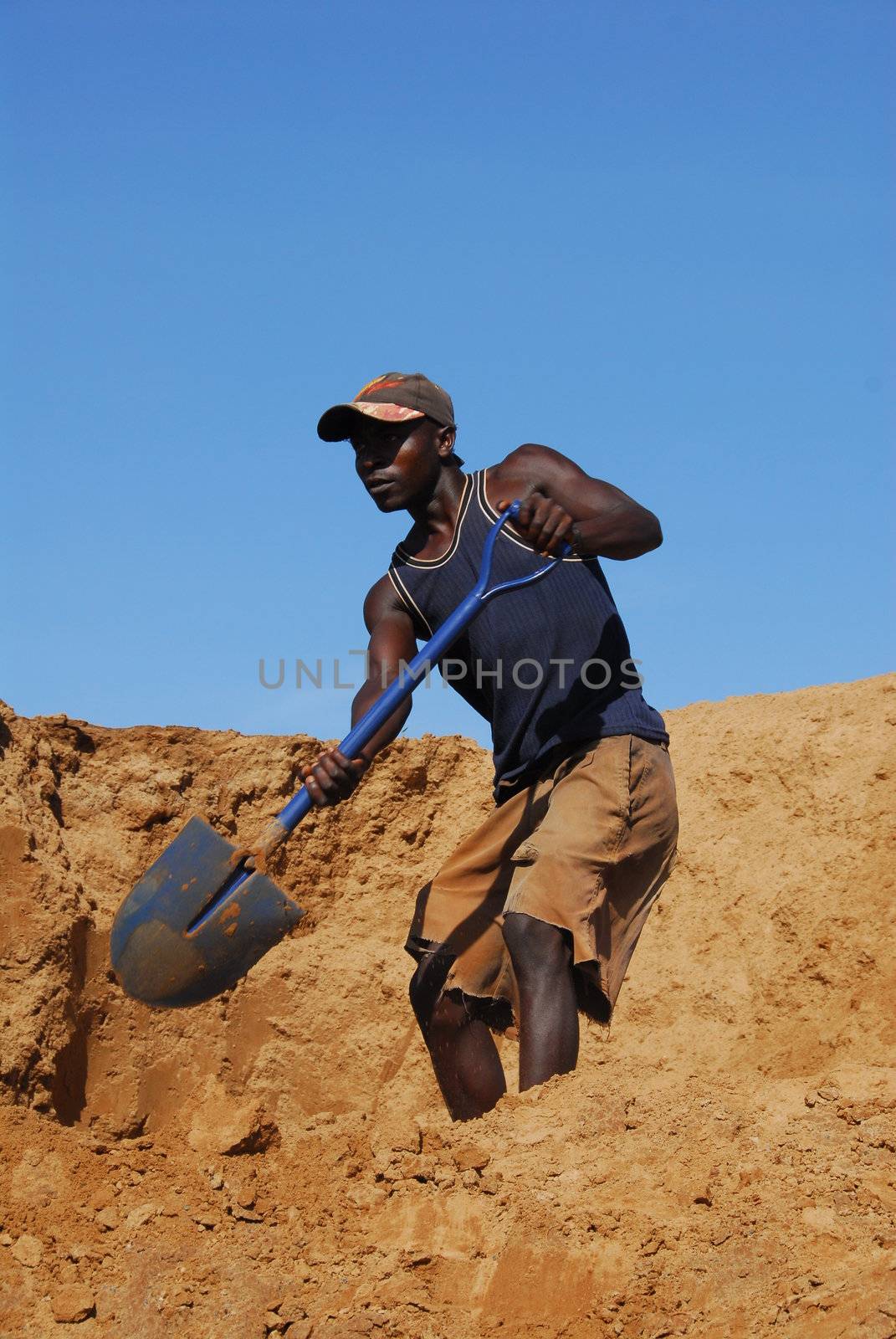 Shinyanga, Tanzania March 18, 2010: Miner shoveling sand in a gold mine. Tanzania is the third gold producer in Africa after Ghana and South Africa.