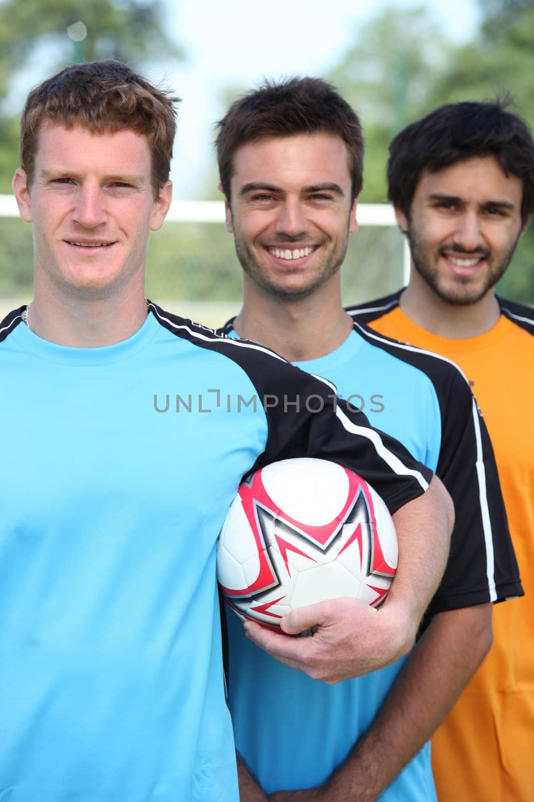 Three smiling young football players by phovoir