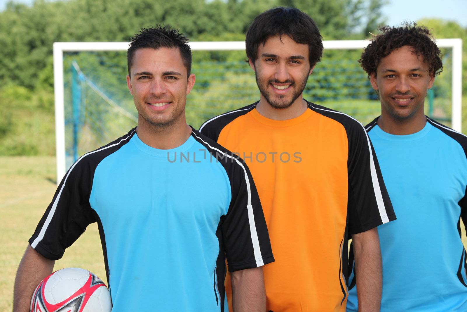 Three football players standing in front of goal by phovoir