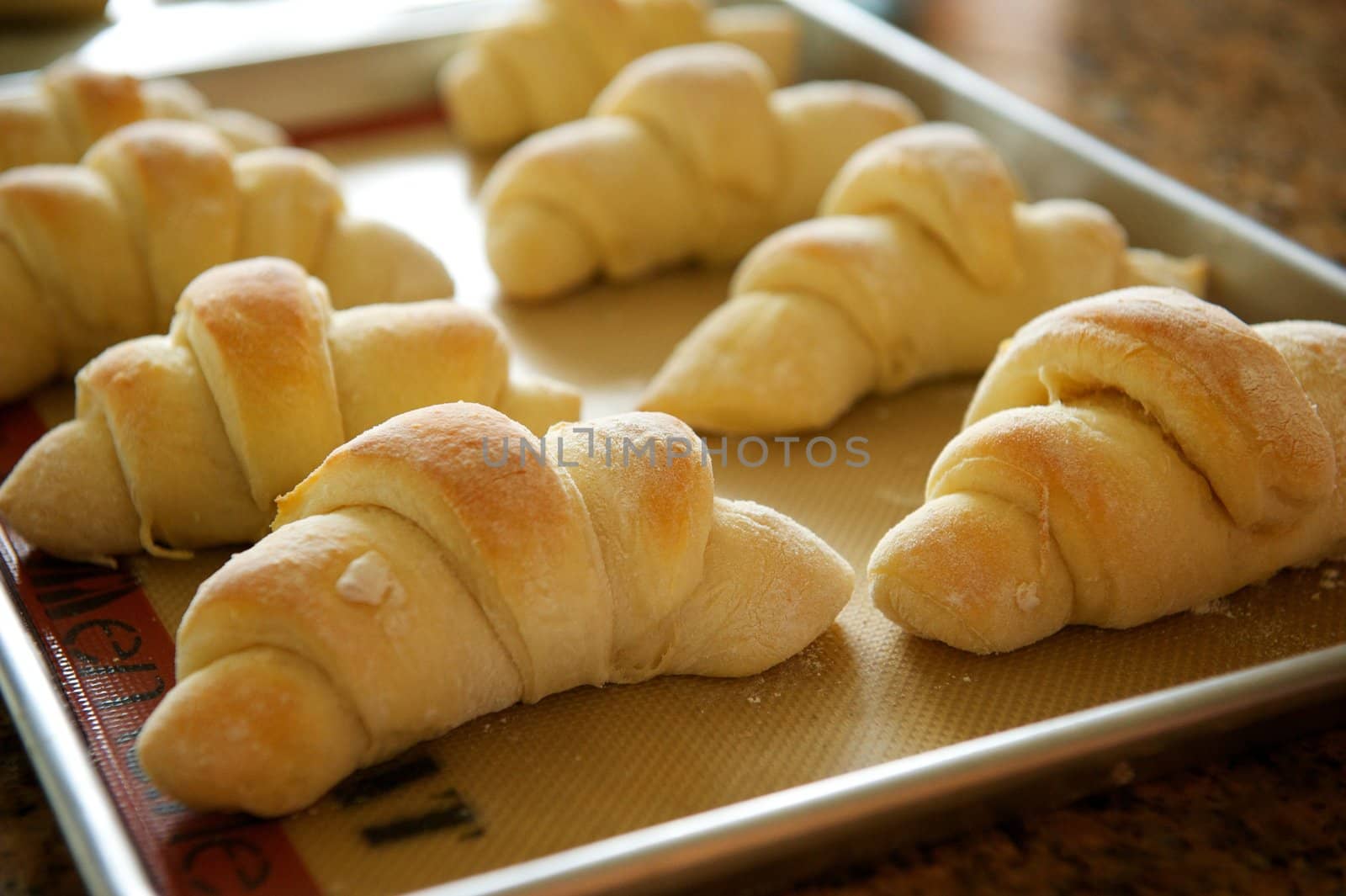 A metal tray of fresh baked holiday rolls for a Thanksgiving type setting