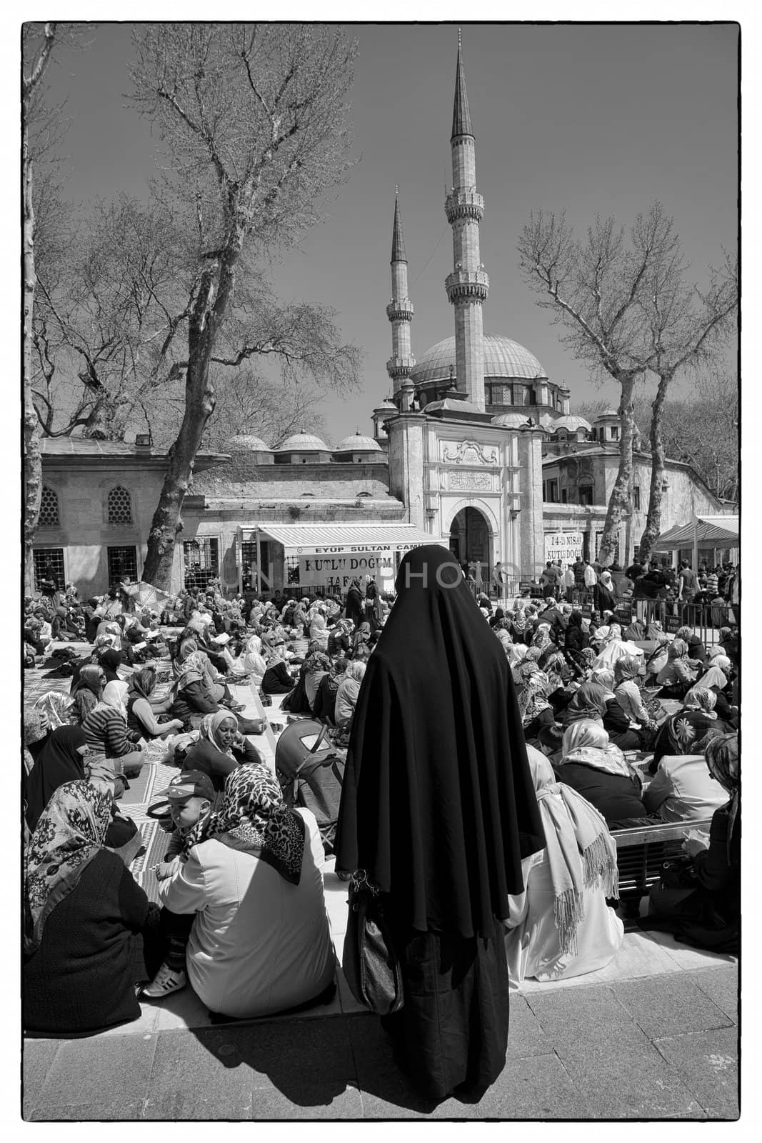 EYUP SALIM MOSQUE, ISTANBUL, TURKEY, APRIL 13, 2012: Just before the Friday prayer in front of the Eyup Salim mosque, Istanbul, Turkey. The women gathered in the sun and the men under some sunblinds.