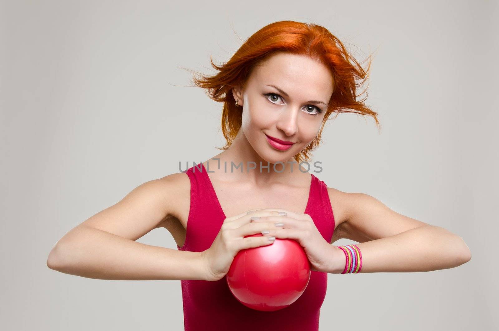 Beautiful fitness model posing with fit ball wearing red swimsuit