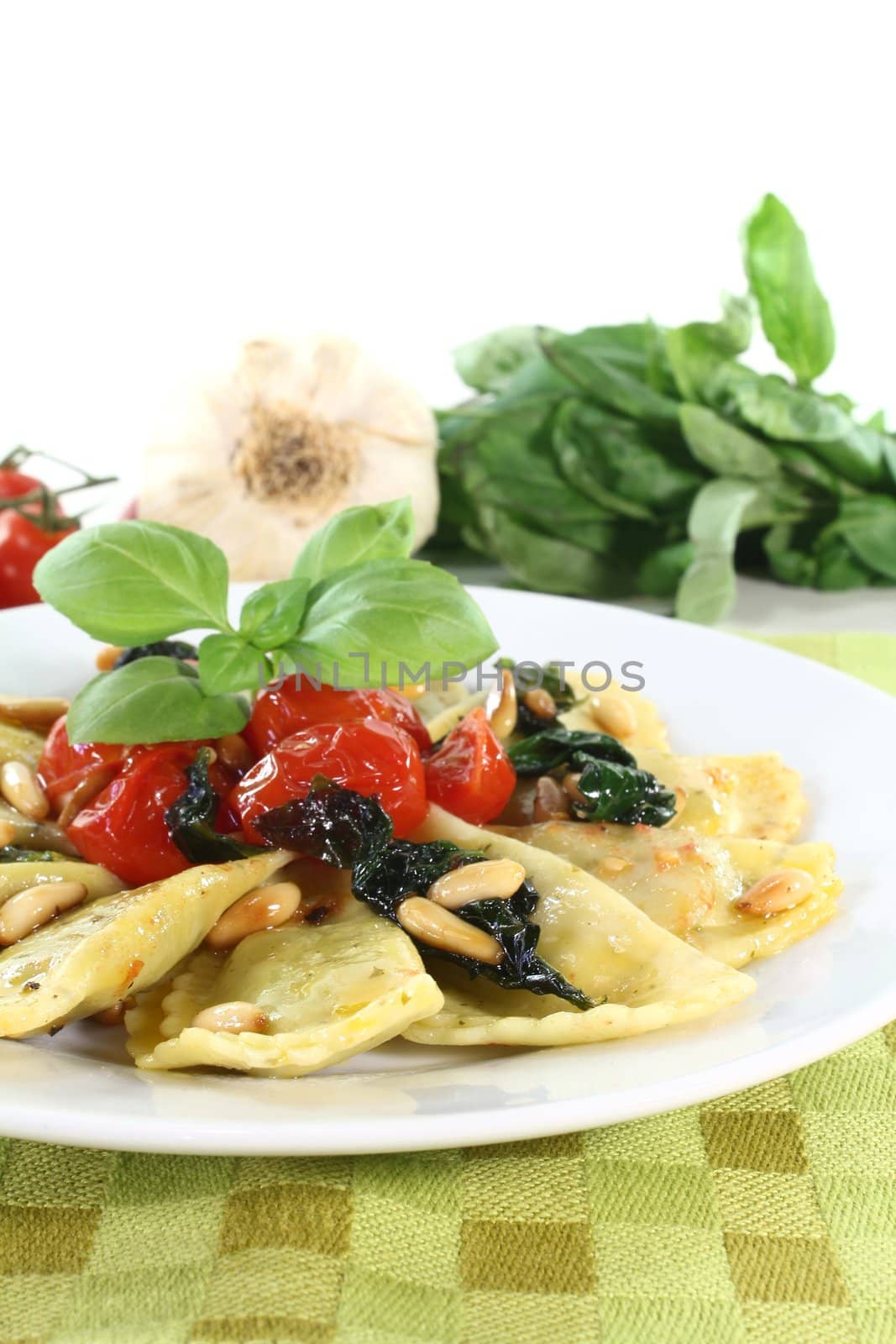 Rocket and Ricotta Cappelletti with pine nuts, tomatoes and basil on a plate