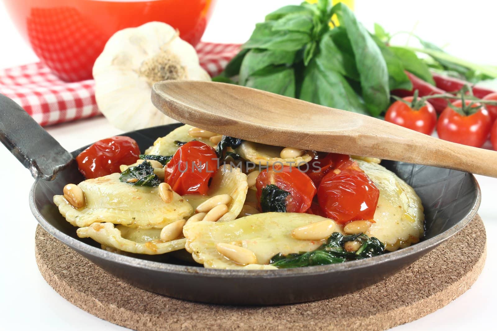 Rocket and Ricotta Cappelletti with pine nuts, tomatoes and basil in a pan