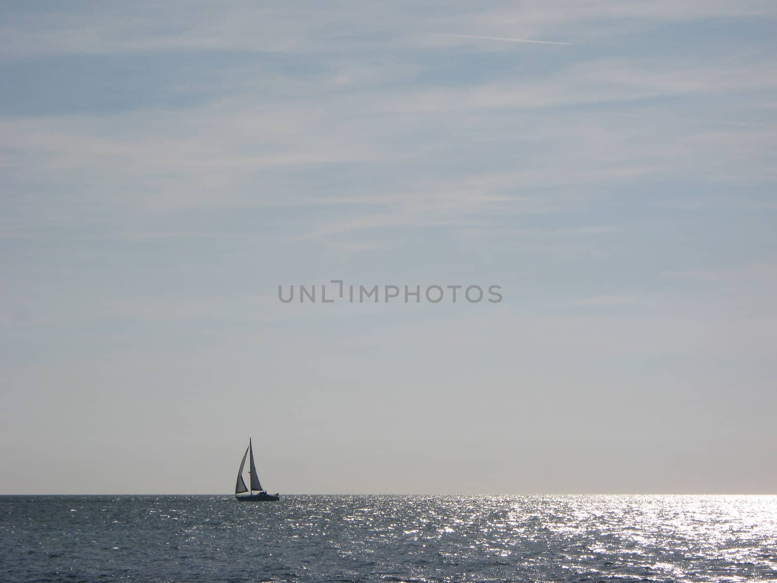 Horizon over the sea with a yacht sailing from right to left.