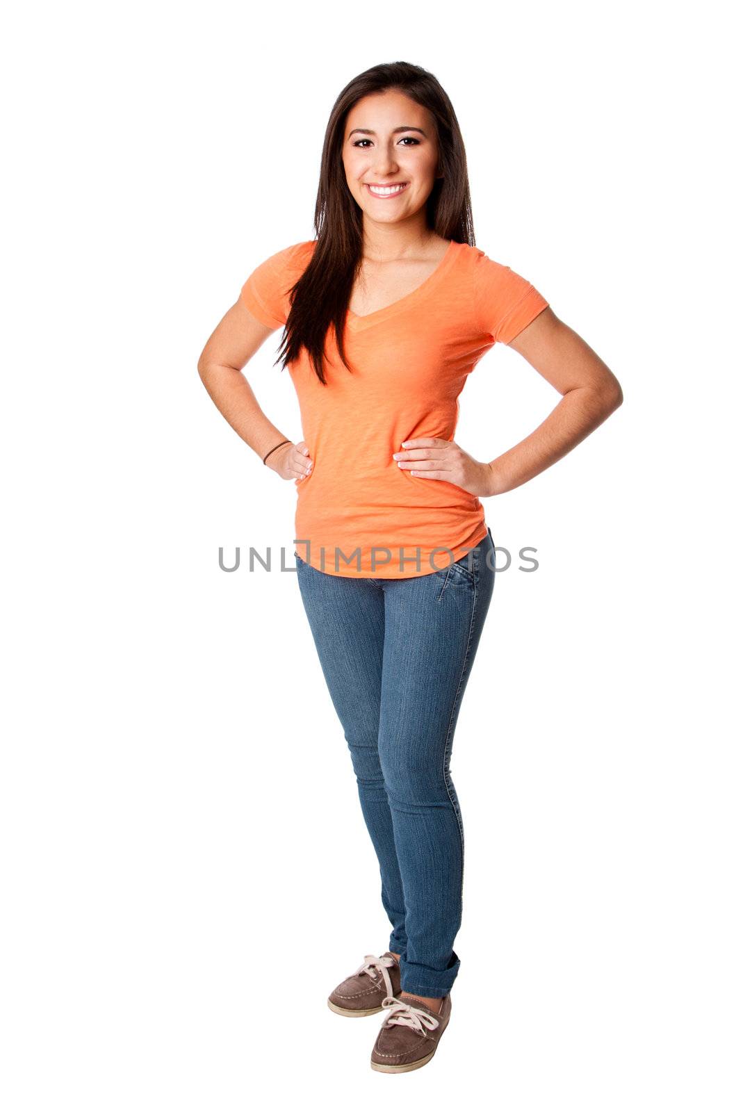 Beautiful happy smiling confident teenager young woman standing with hands on hip wearing orange shirt and blue jeans, isolated.