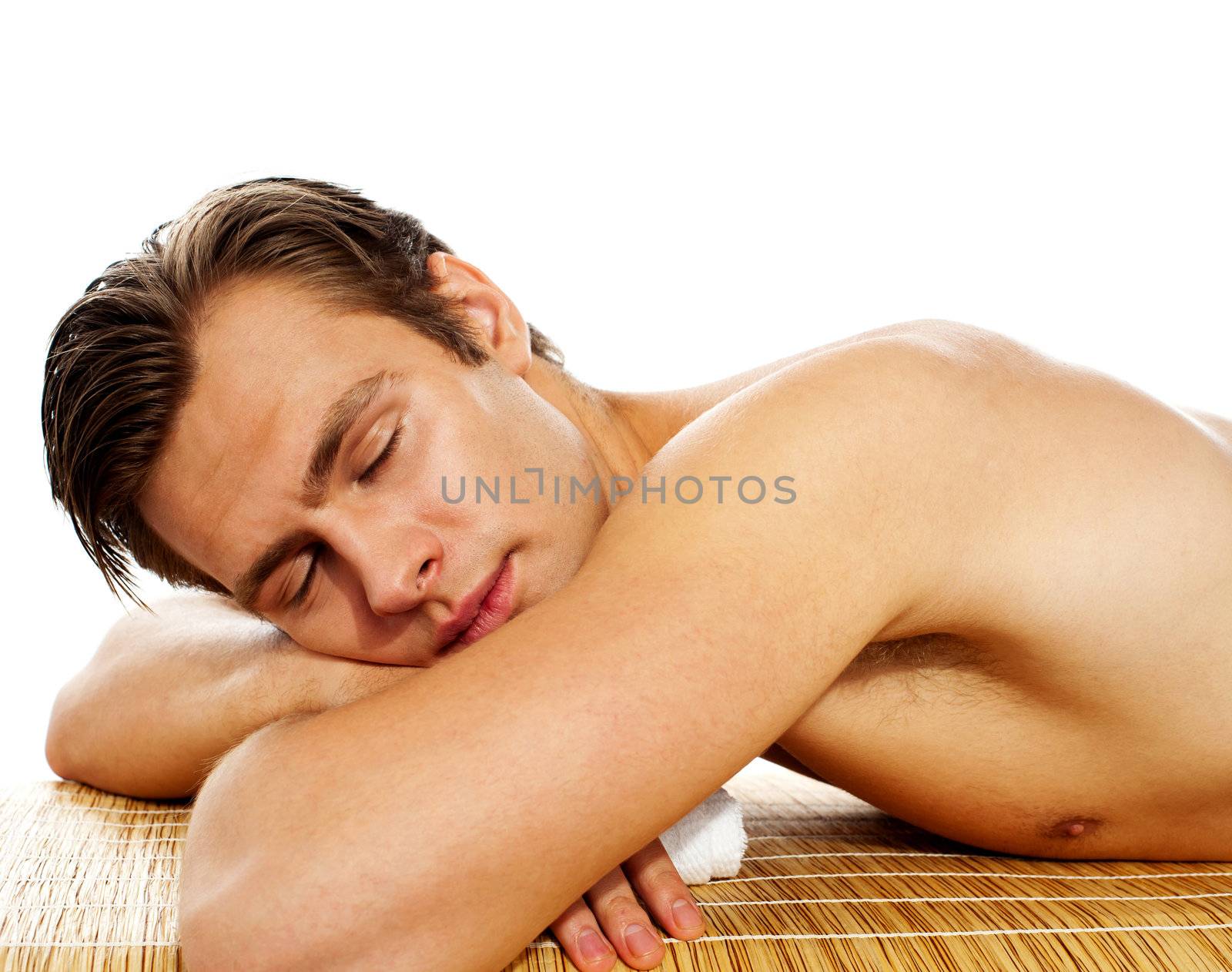 Young man enjoying the treatment in spa salon on white background