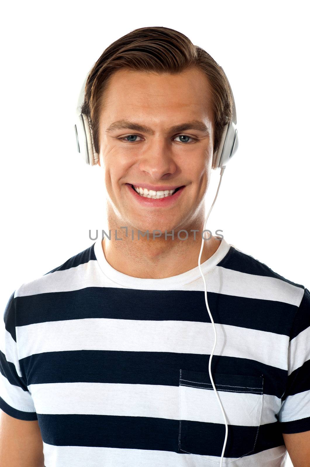 Smiling young man listening to music through headphones by stockyimages