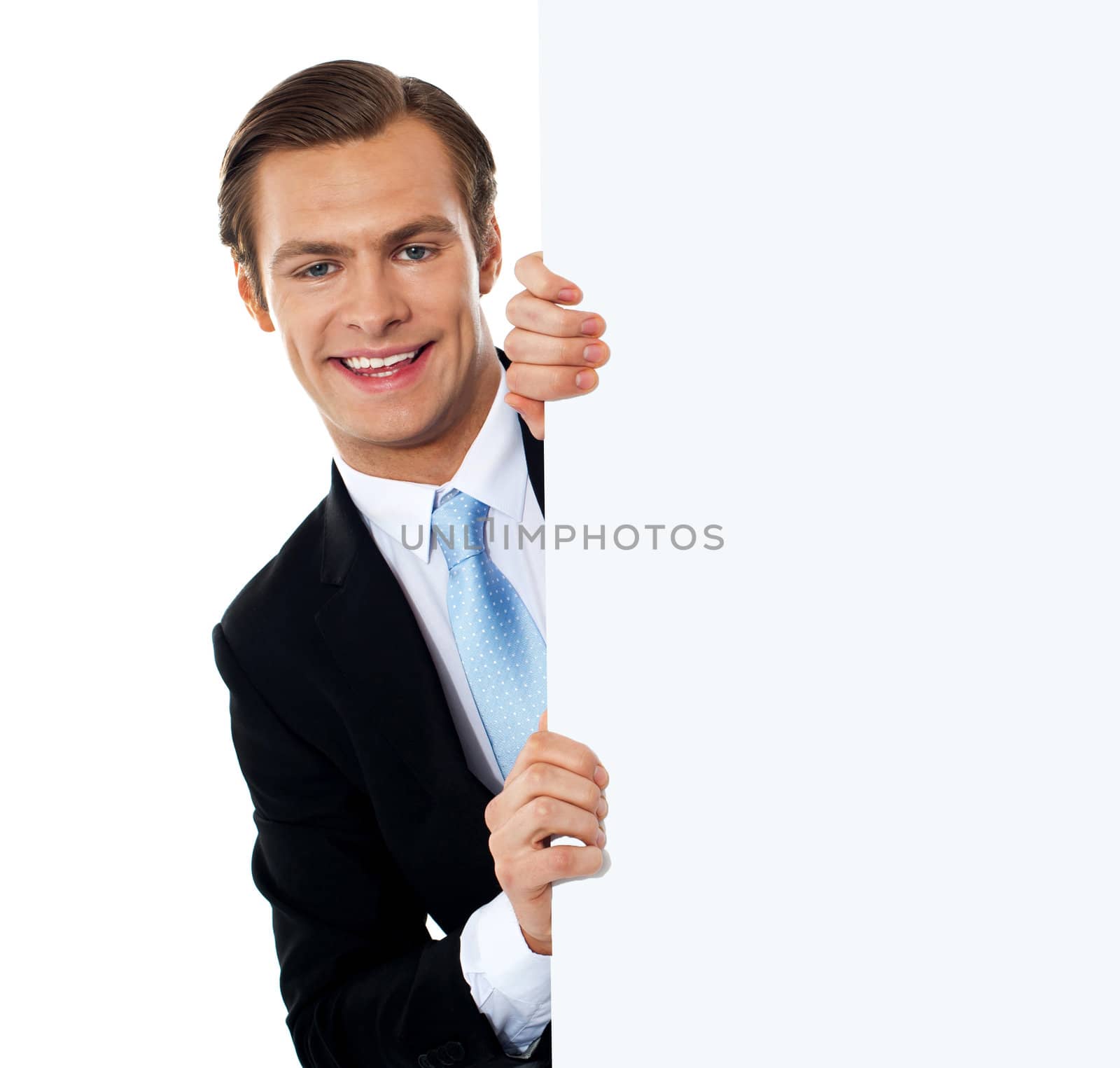 Smiling business professional behind blank clipboard by stockyimages