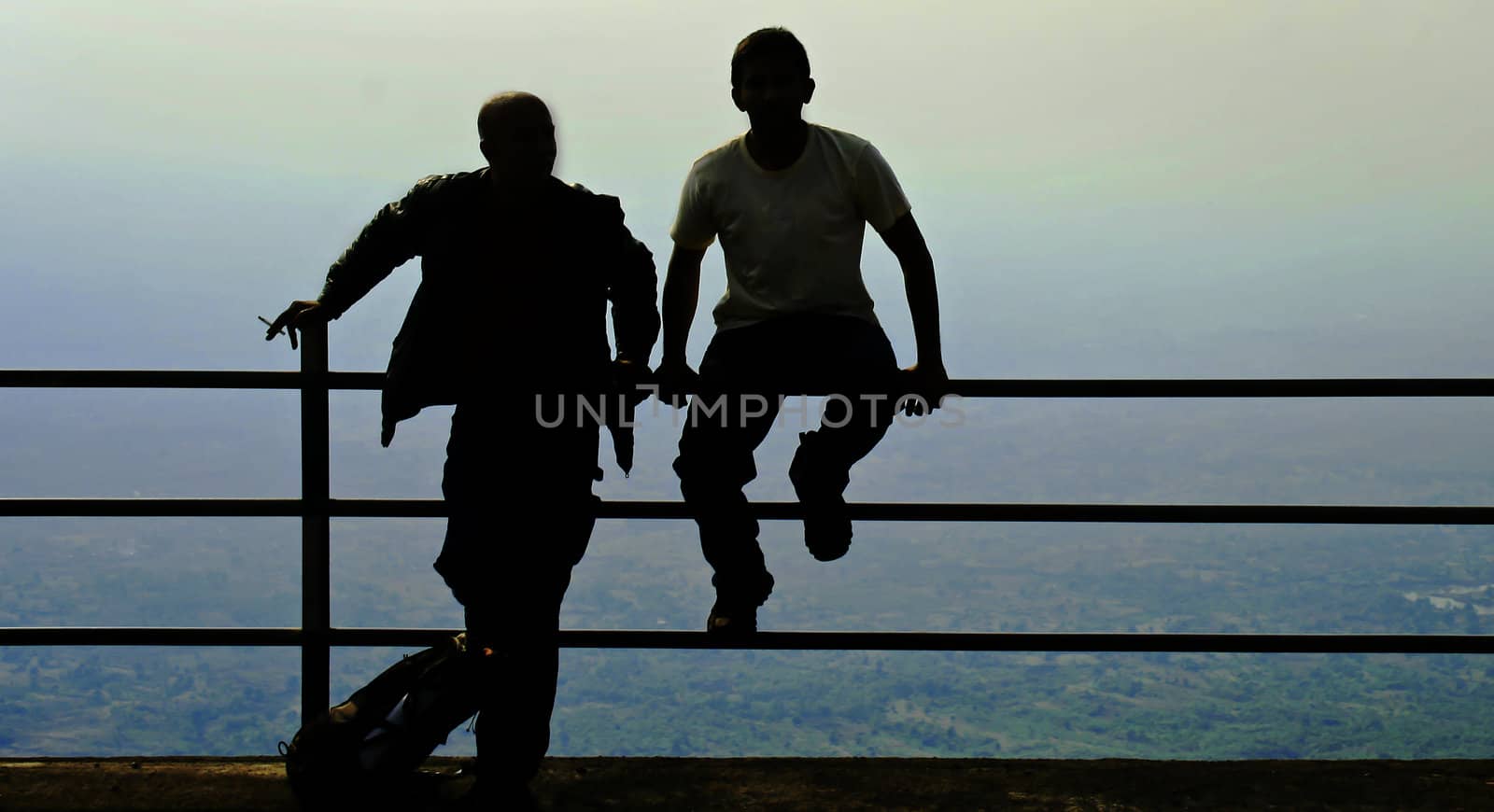 Generic scene of tourist relaxing on reaching a high vantage point having a cigarette