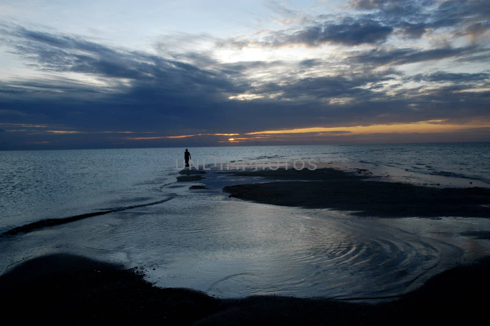 silhouette of a man walking alone on sunrise by antonihalim