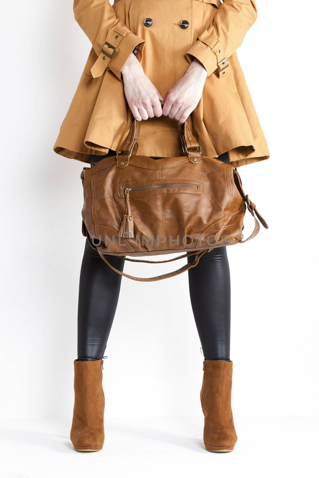 detail of standing woman wearing coat and fashionable brown shoes with a handbag