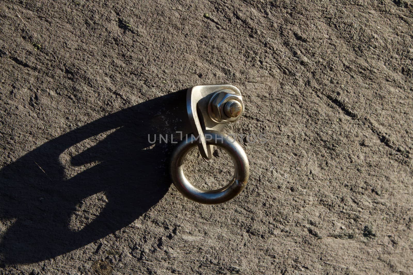 Aluminium safety bolt in place on slate rock with ring and nut.