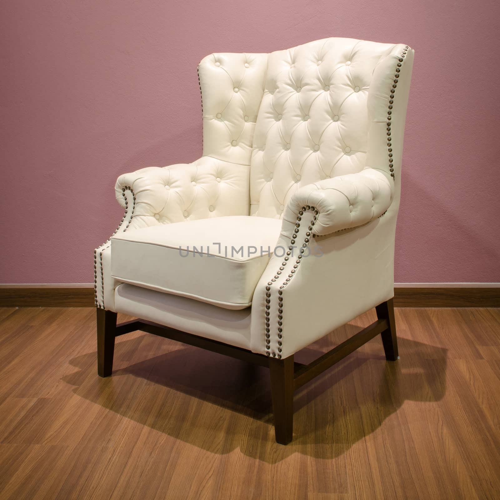 Side of Classic Chesterfield luxury White Leather armchair on Wood floor