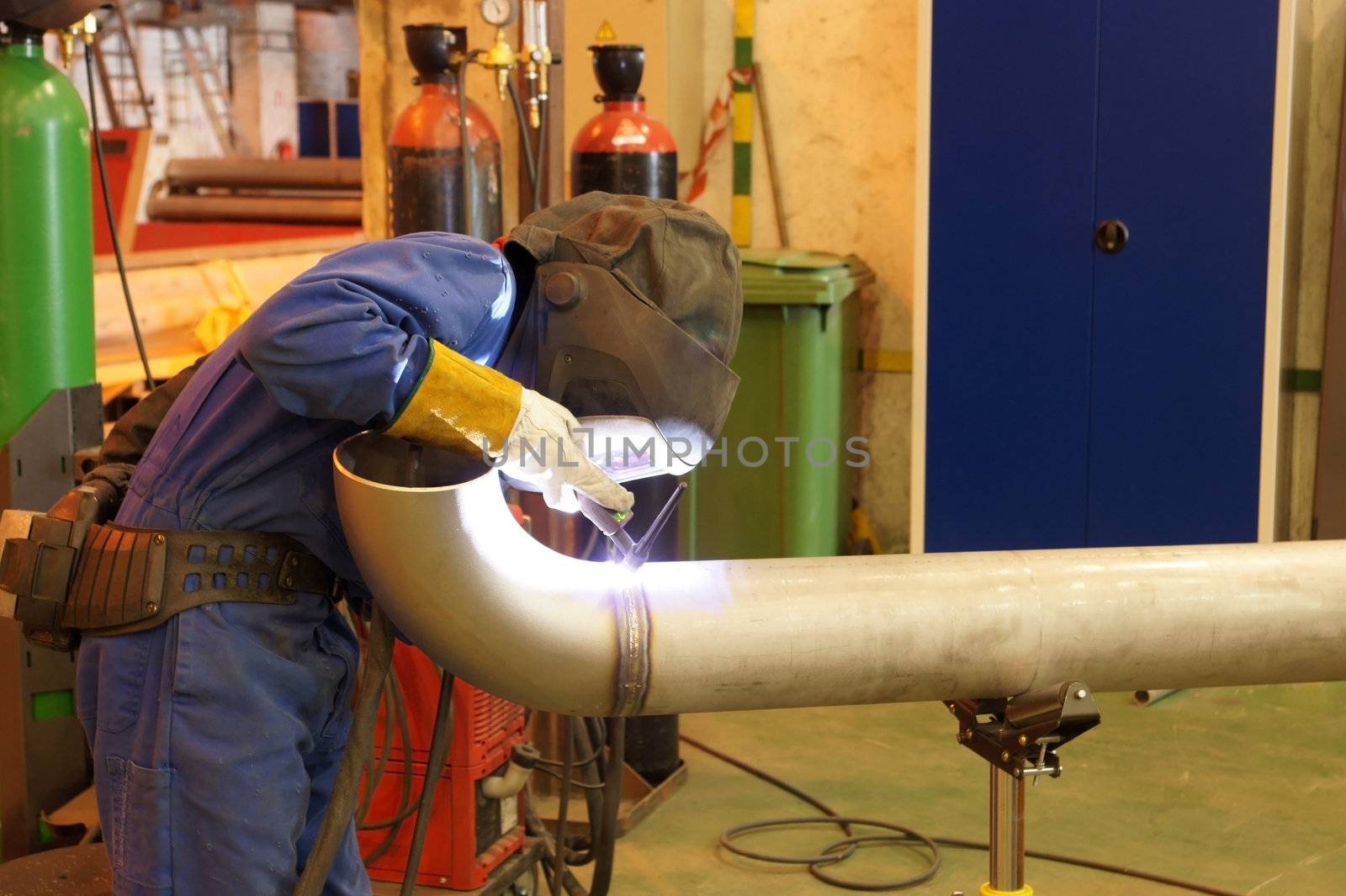 Factory worker welding  a metal pipe