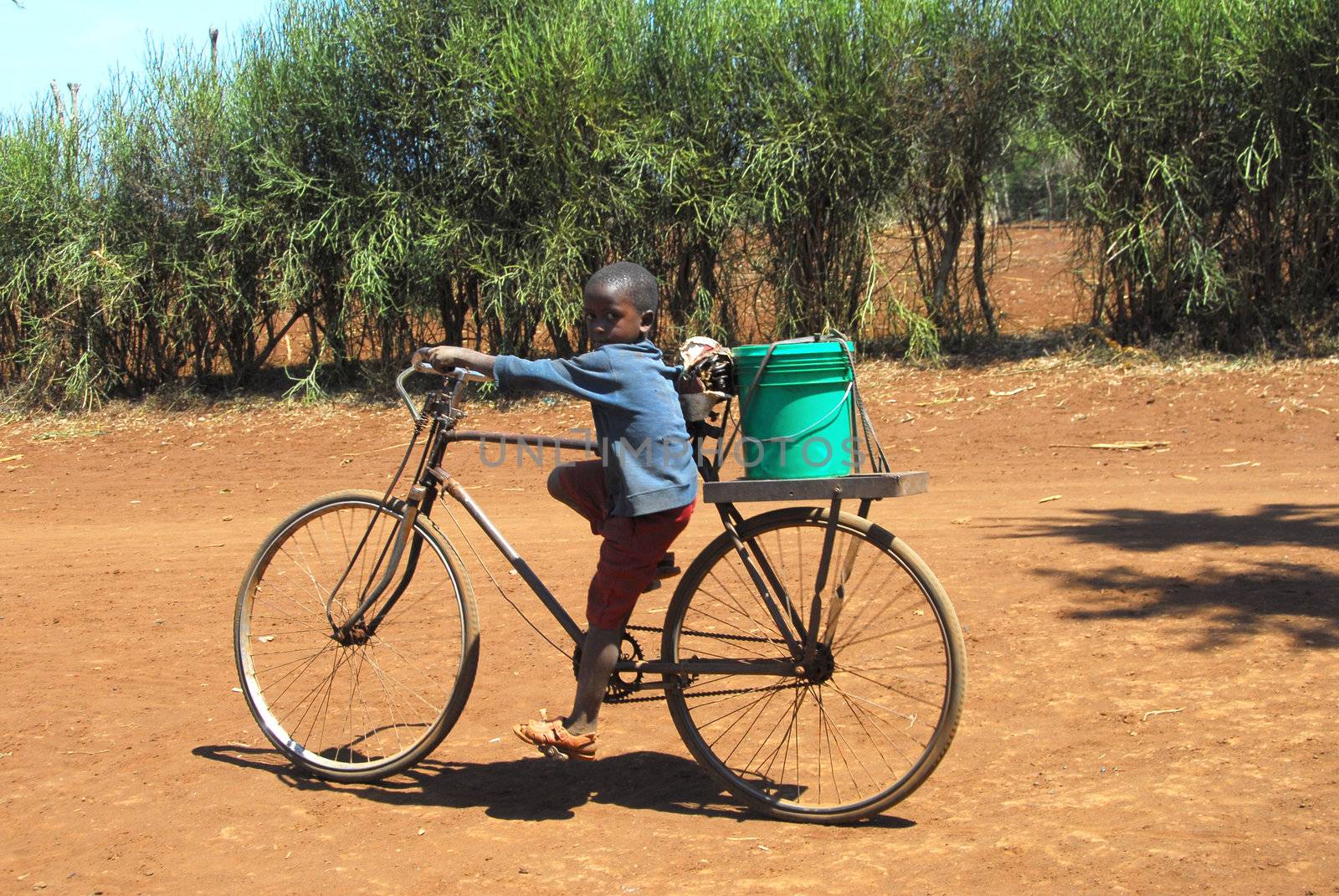 Mtito Andes,Kenya 13 JULY 2009:child carries the water with your bike thanks to various humanitarian organizations,the people of the village of Andes Mtito can fetch water from a source.Mtito Andes is a village close Kilimanjaro and the lack of water is very serious