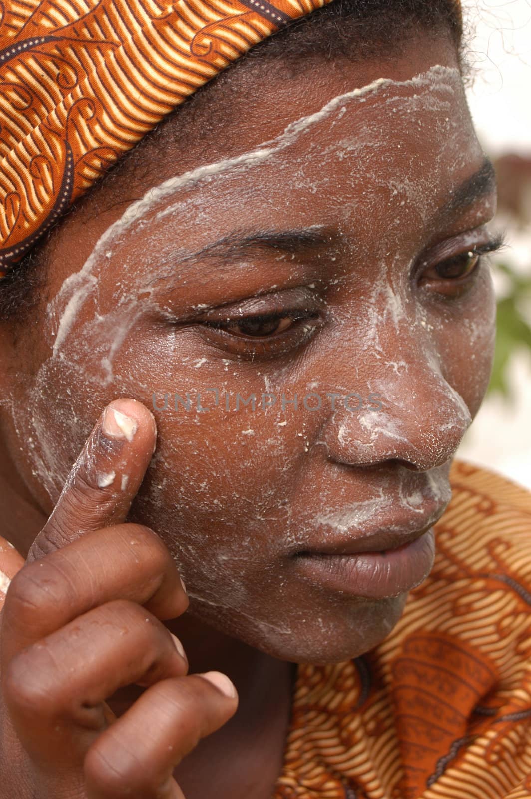 Mozambique Island, Mozambique, may 2, 2004: African woman with the cream of Musiro a paste obtained by rubbing a stone on a piece of a tree branch Olax locale.Il miraculous mixture is used to treat the skin. Does it make it softer and removes stains.