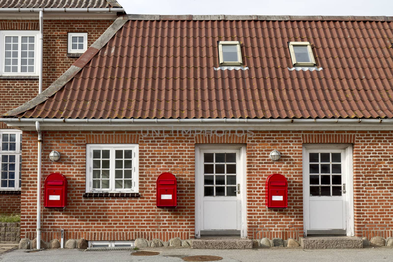 three red mailboxes on stone walled house in denmark