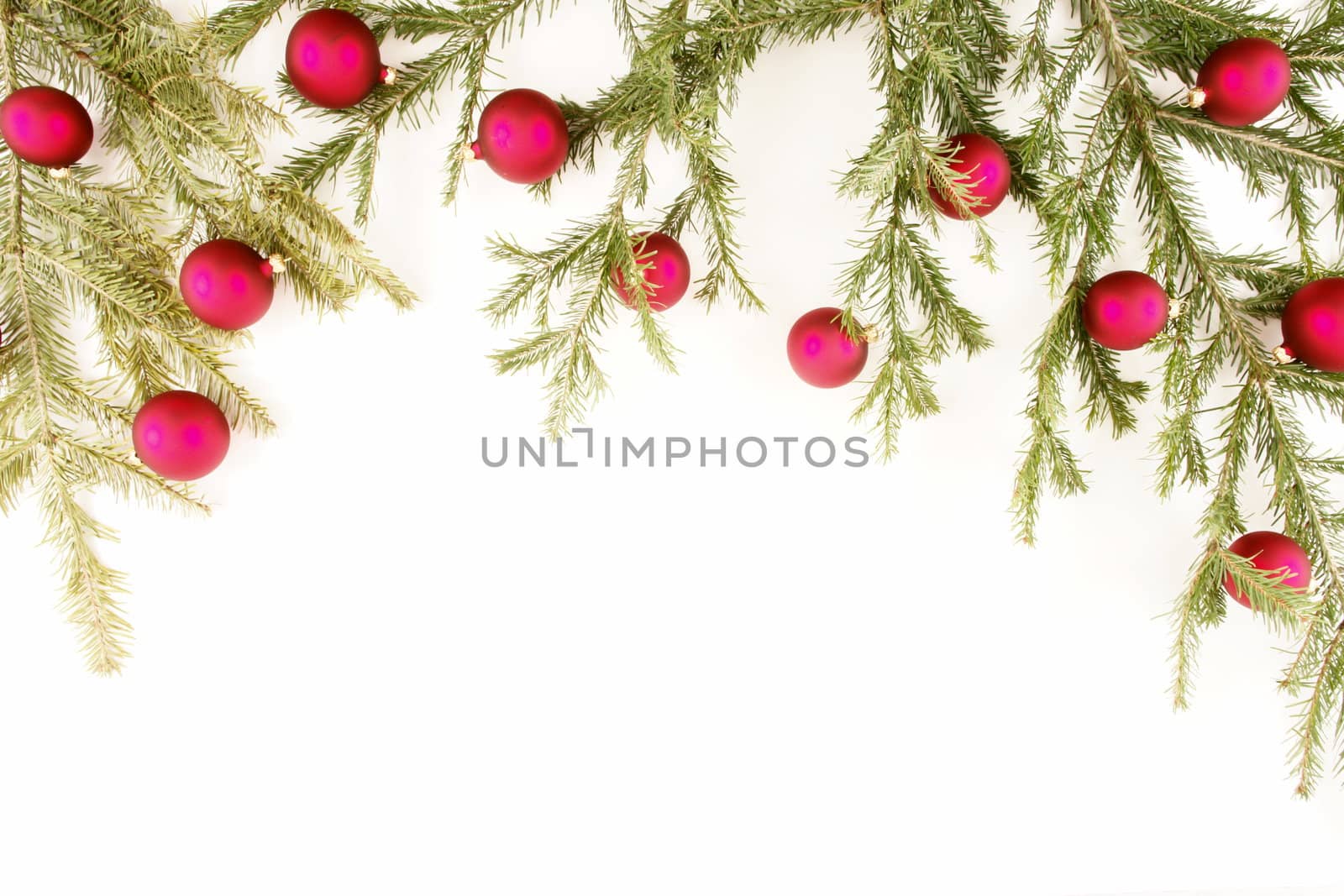 Border of red christmas garland with baubles and ribbons on white.