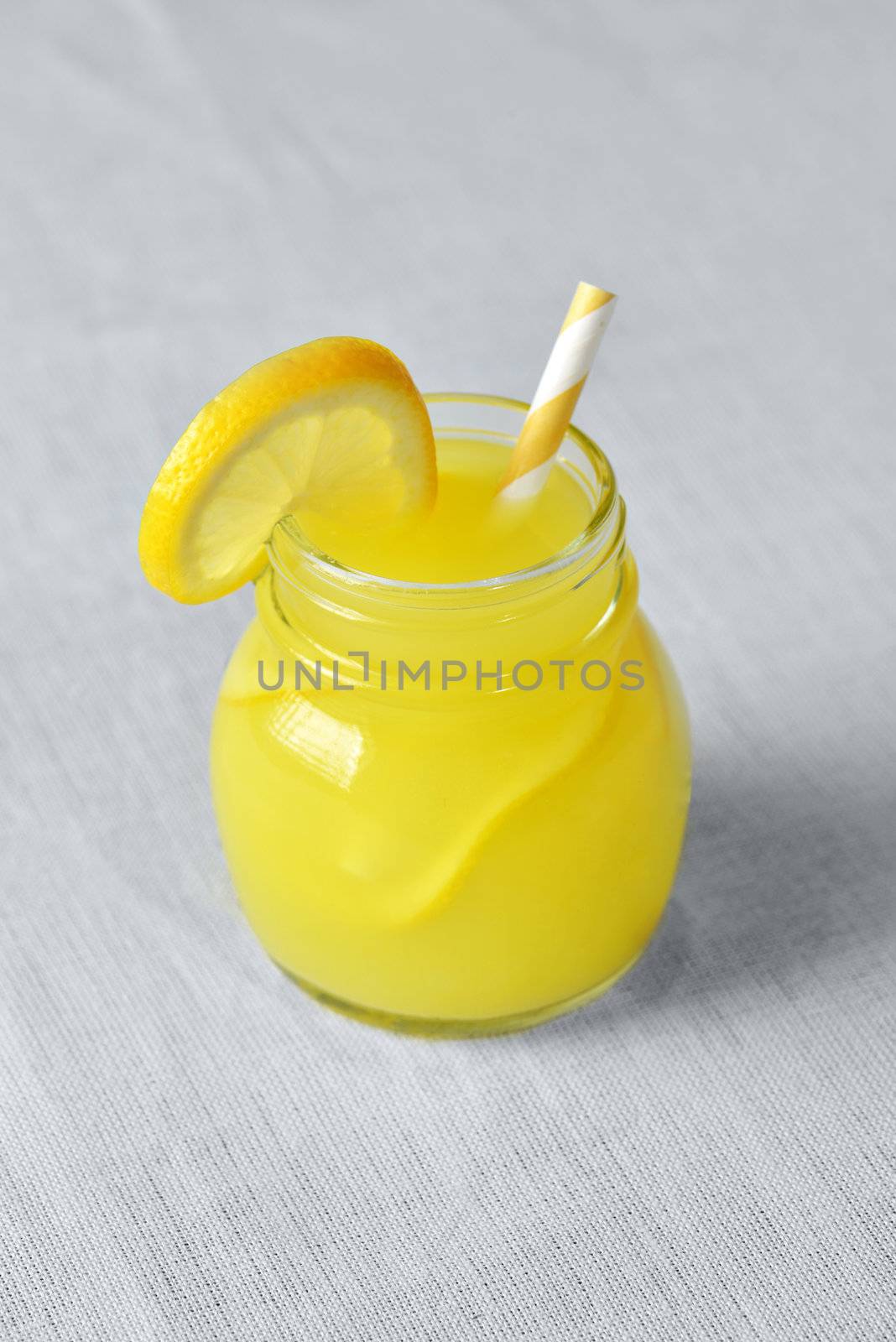 Lemonade in a Mason Jar with yellow striped straw and lemon wedge