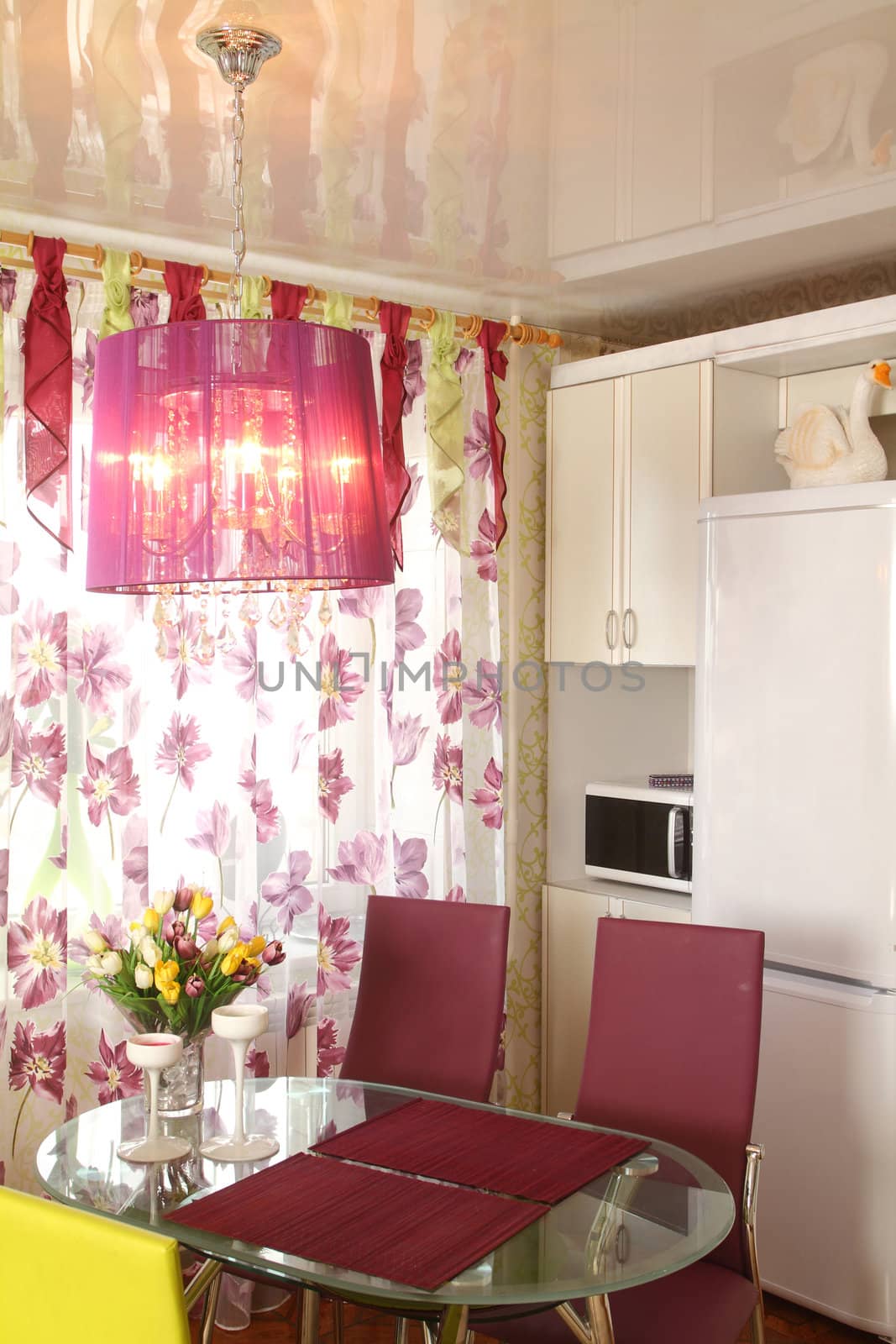 Modern kitchen. A bunch of flowers on a glass little table opposite to a window