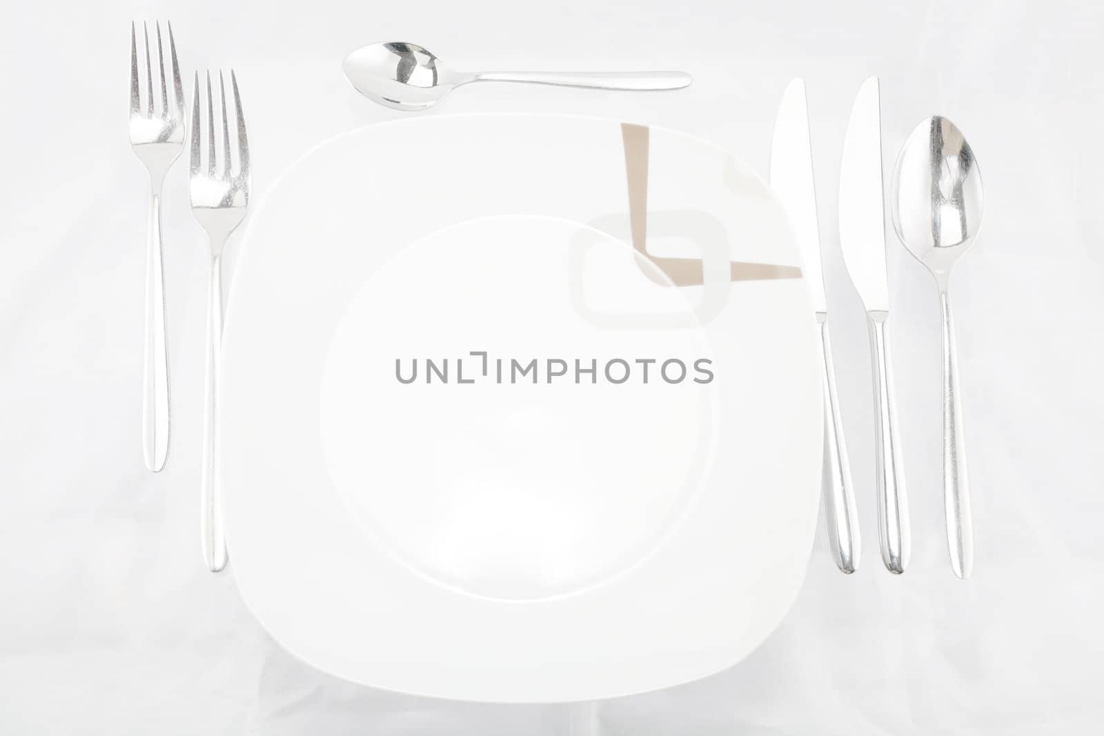 Plates with a silver fork, spoon, dessert spoon and a knife