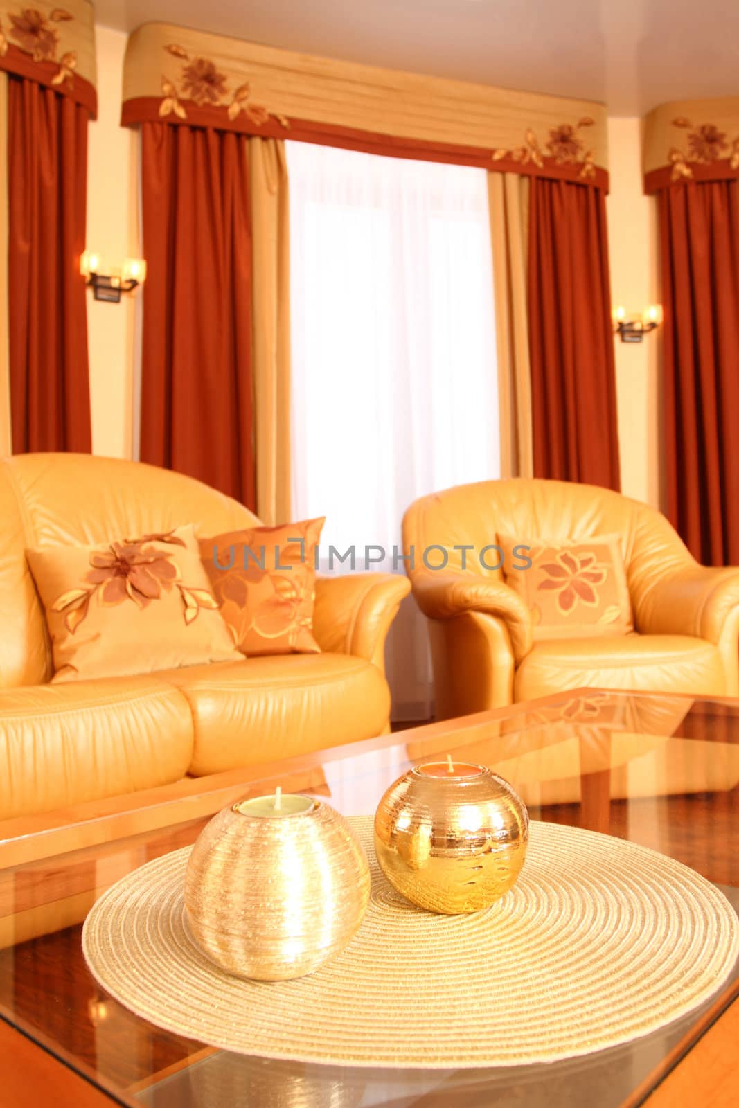 spacious hall with leather sofas and the embroidered pillows on them and big windows, in the foreground a little table with candles