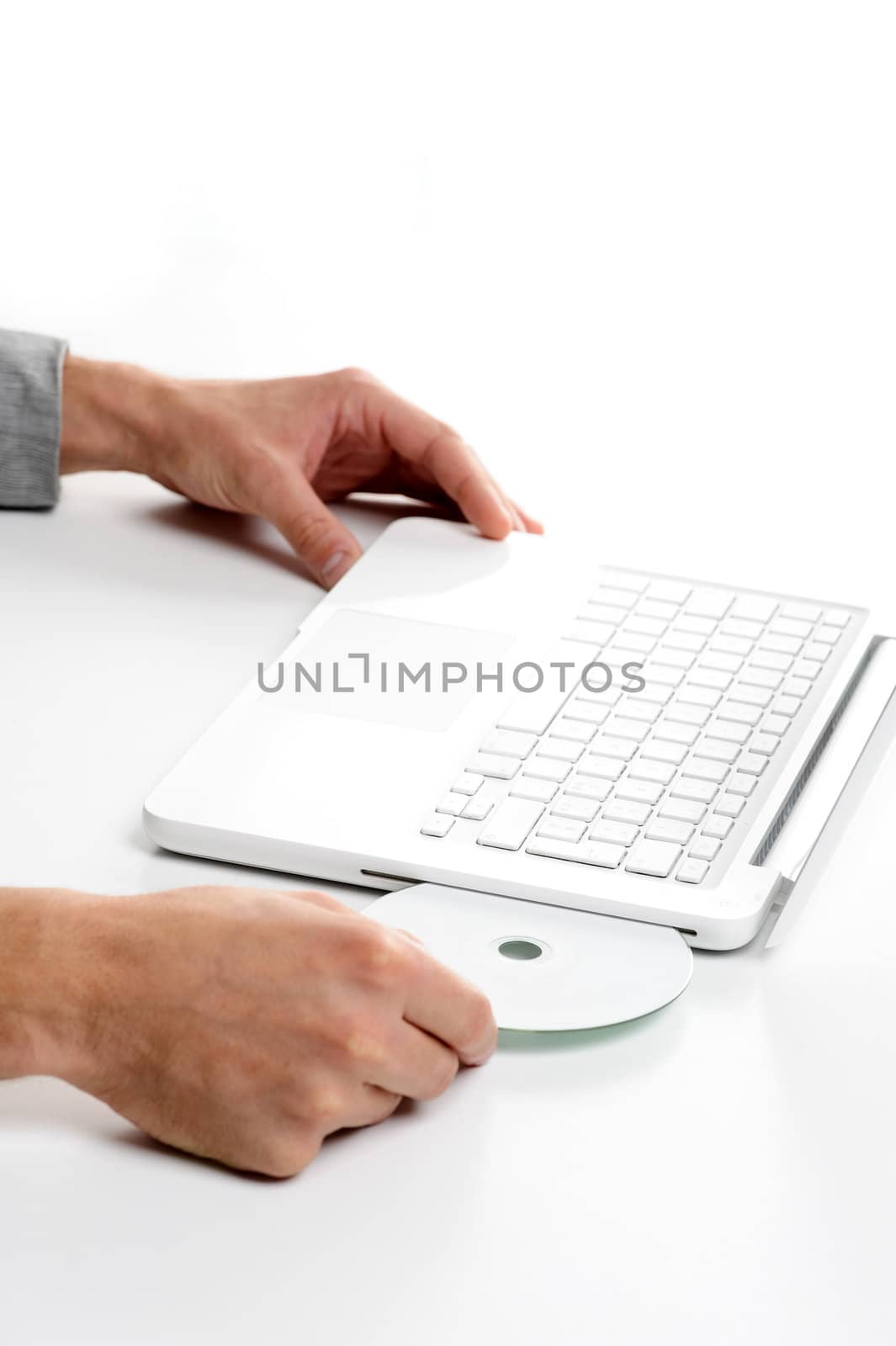 Businessman inserting a cd on white laptop by stokkete