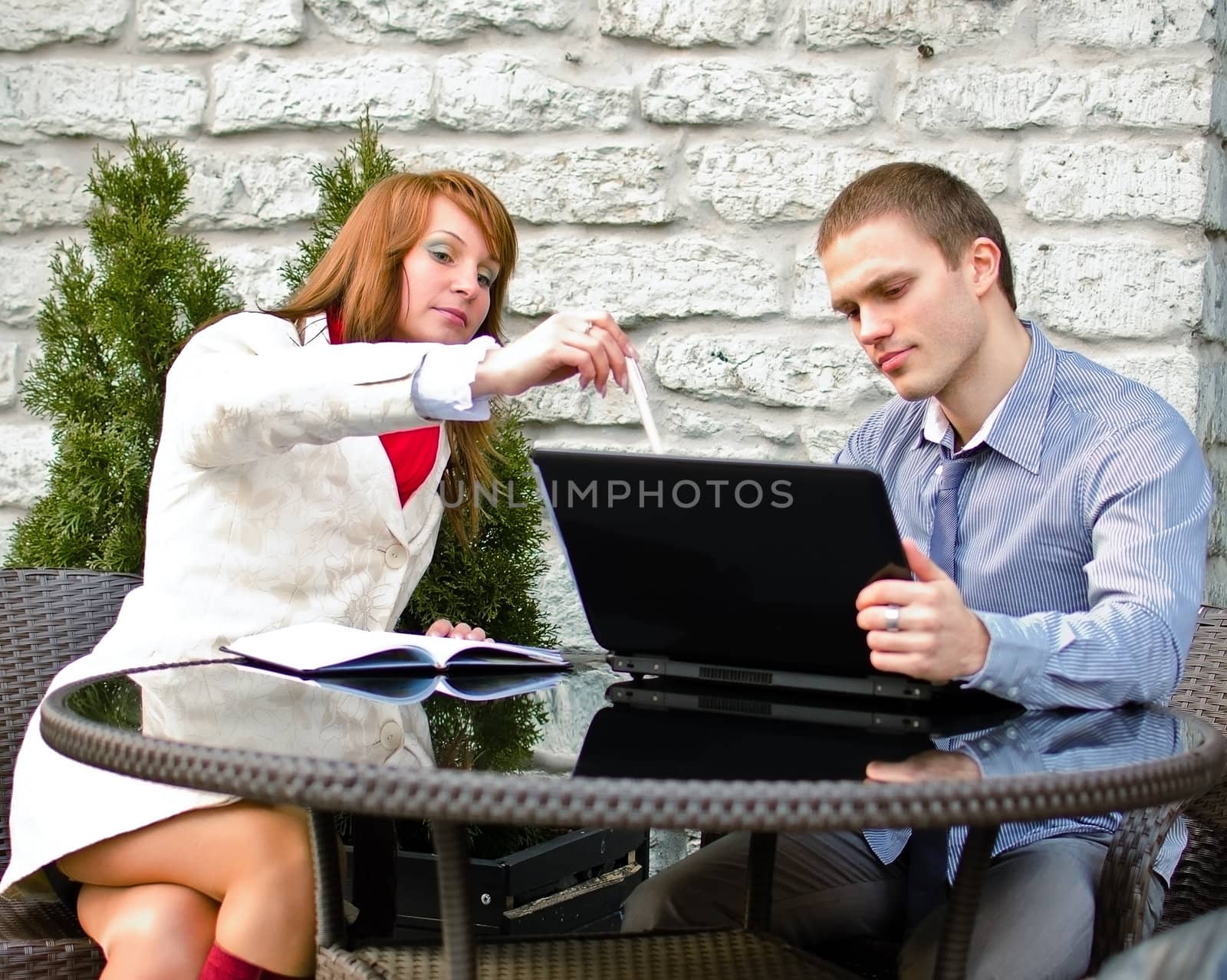 Business partners meeting: Male and female with laptop sitting outdoors