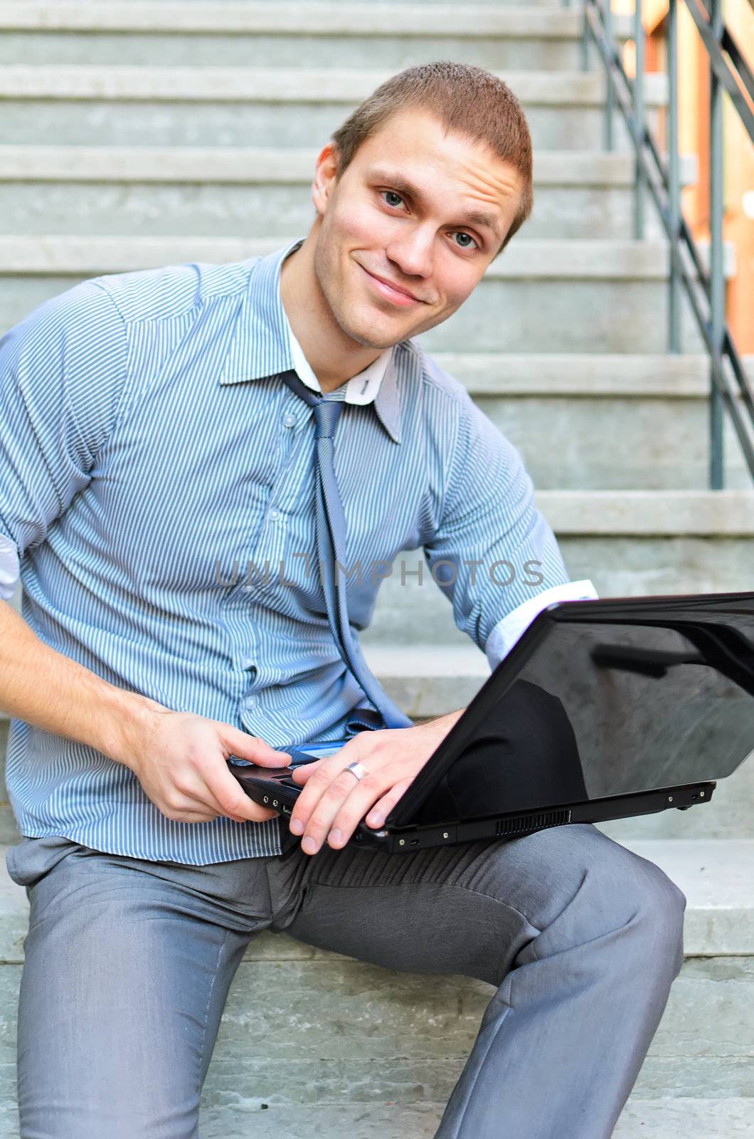 Young guy with a laptop sitting on the stairs