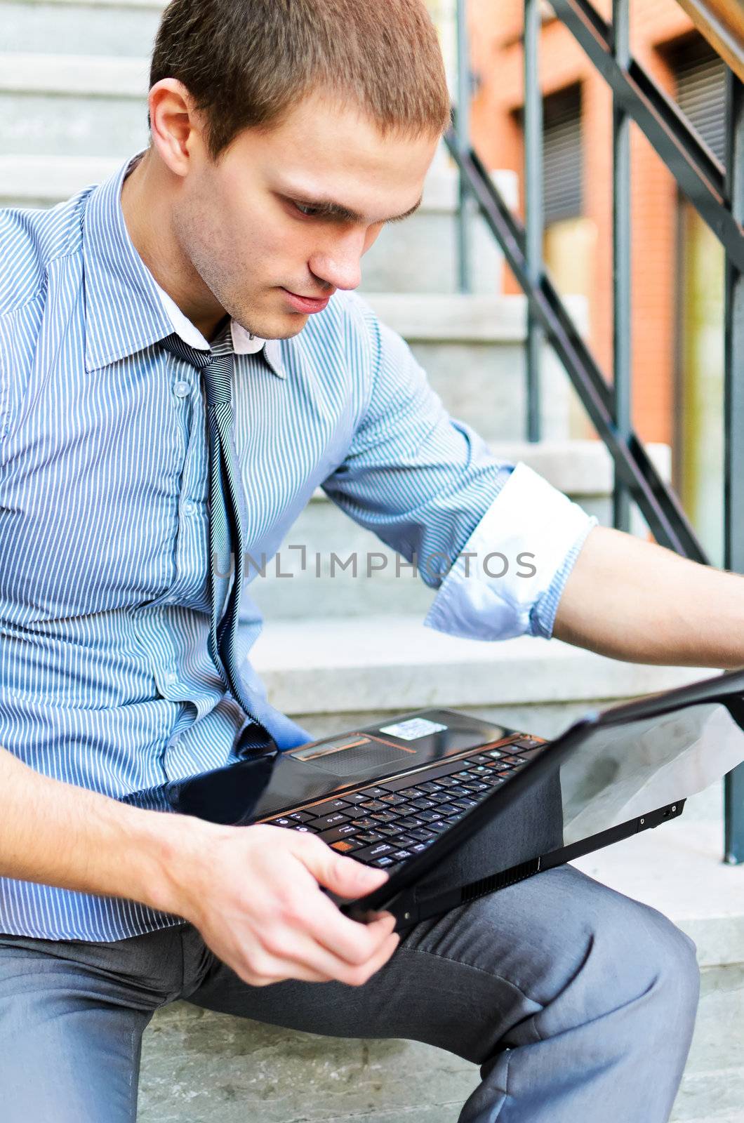 Young guy with a laptop sitting on the stairs