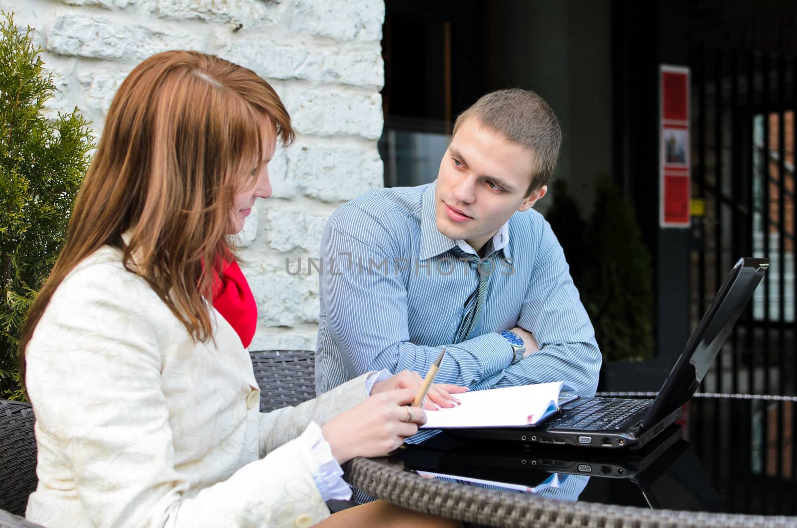 Business partners meeting: Male and female with laptop sitting outdoors