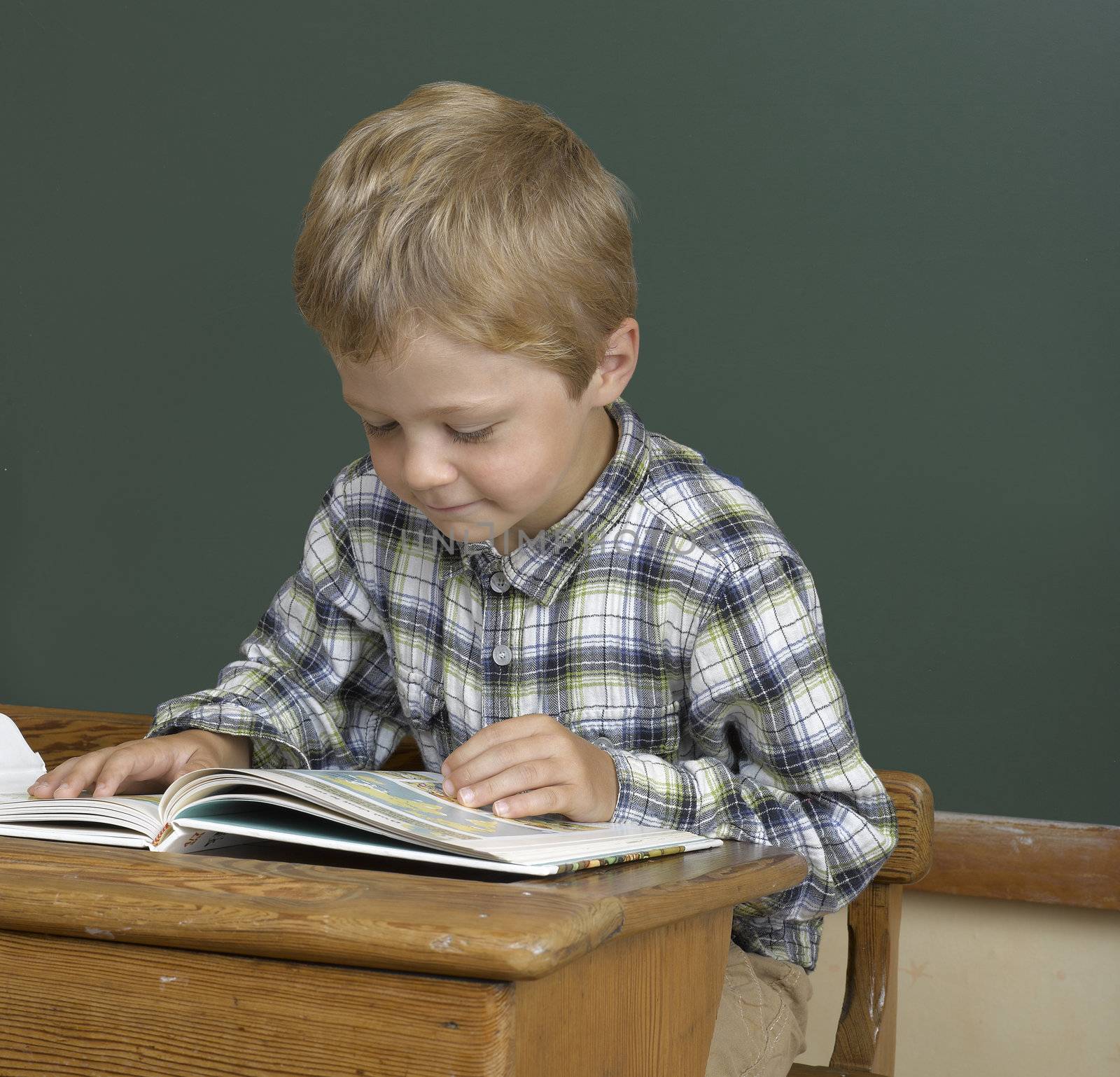 jeune garçon sur un banc d'école devant un fond de tableau 