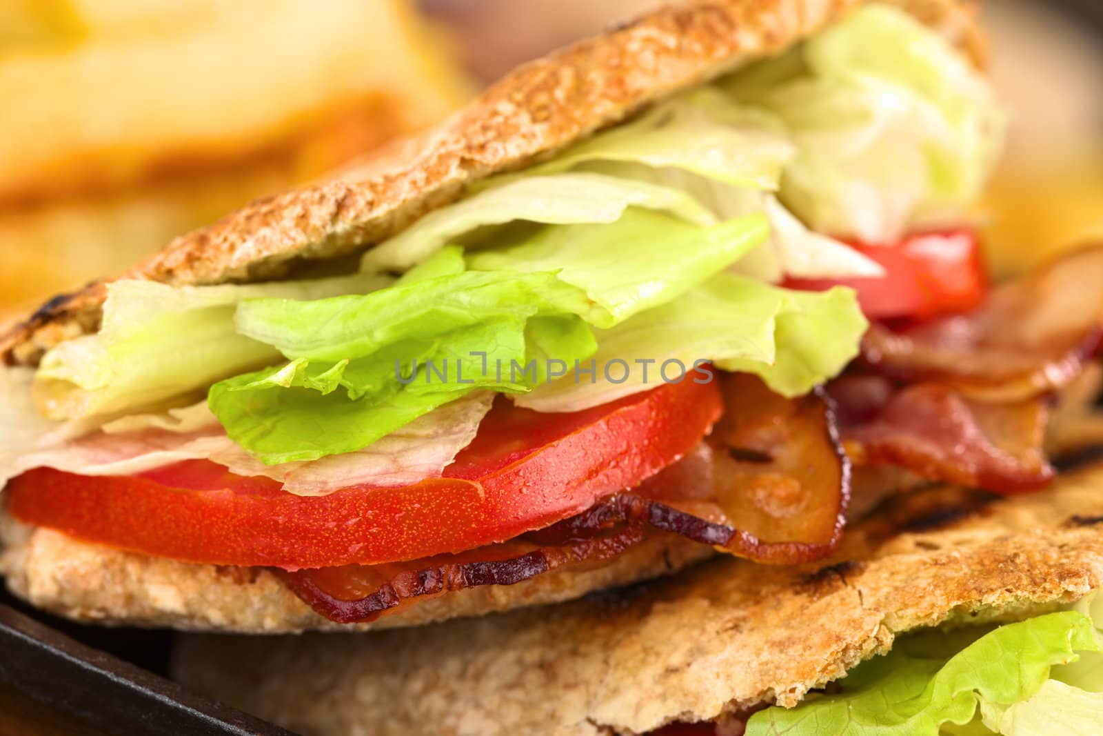 Fresh homemade BLT (bacon lettuce and tomato) wholewheat pita sandwich (Selective Focus, Focus on the front of the upper pita stuffing) 