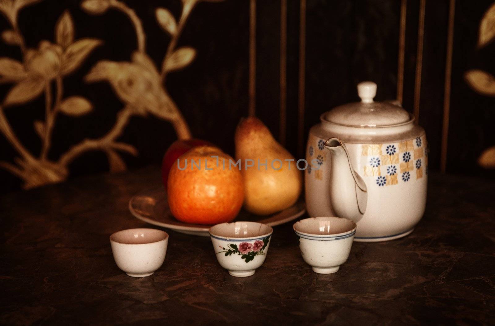 still life low key image of a tea pot cups and fruit