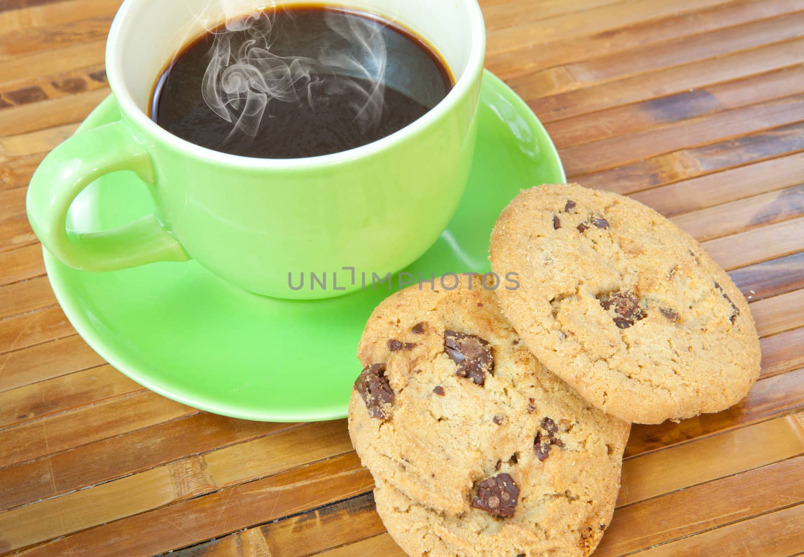 Chocolate chip cookies with cup of coffee on wood background