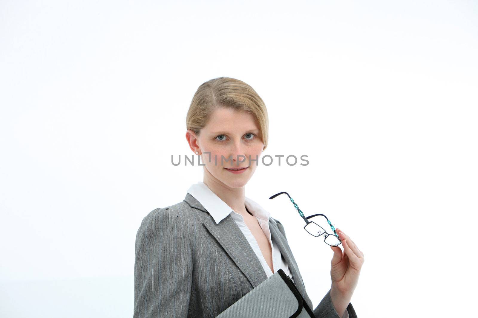 Serious businesswoman with her glasses in her hand and carrying a folio watching the camera and listening