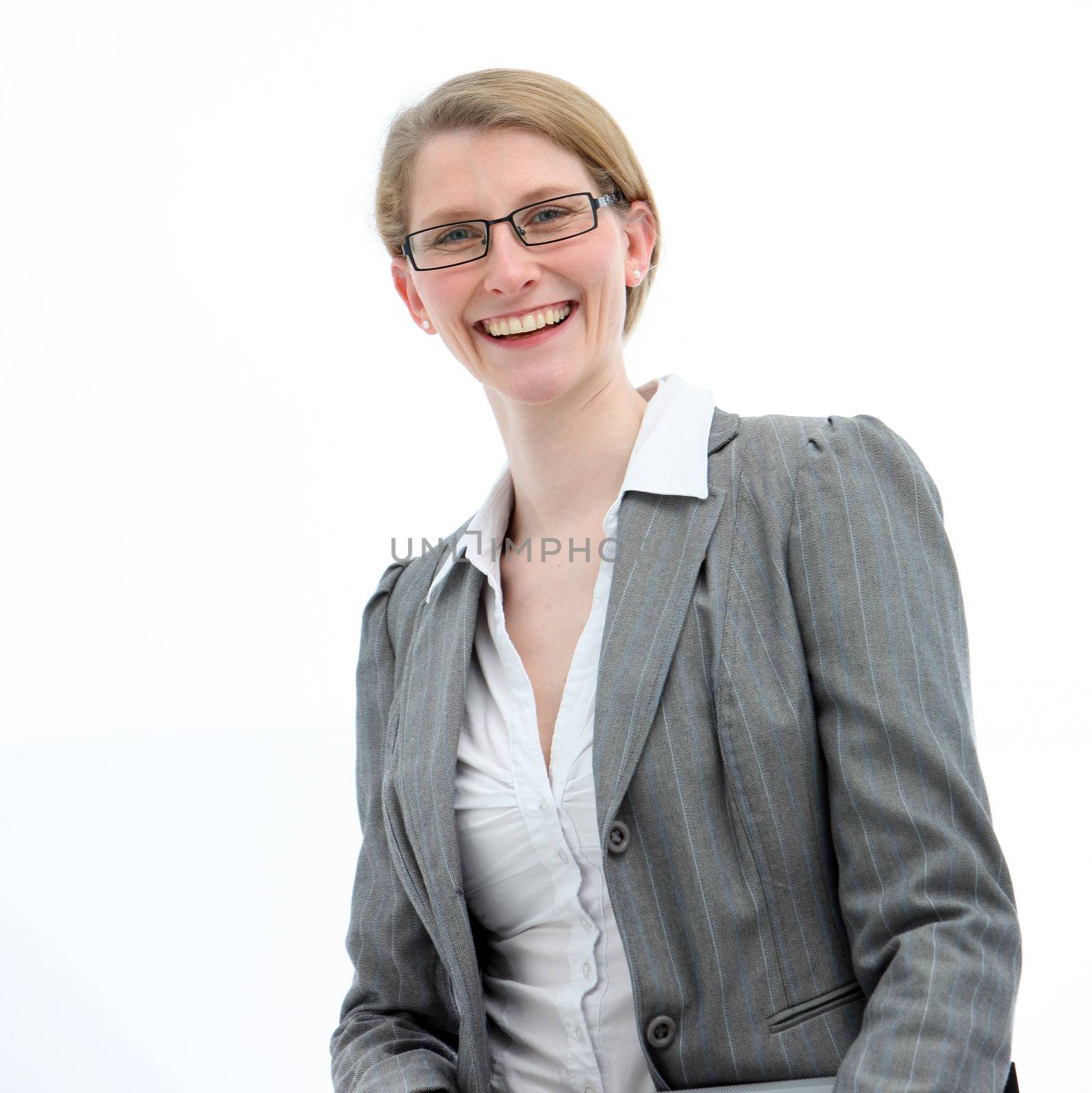 Friendly businesswoman with a beaming smile wearing a stylish grey jacket and glasses looks down into the camera