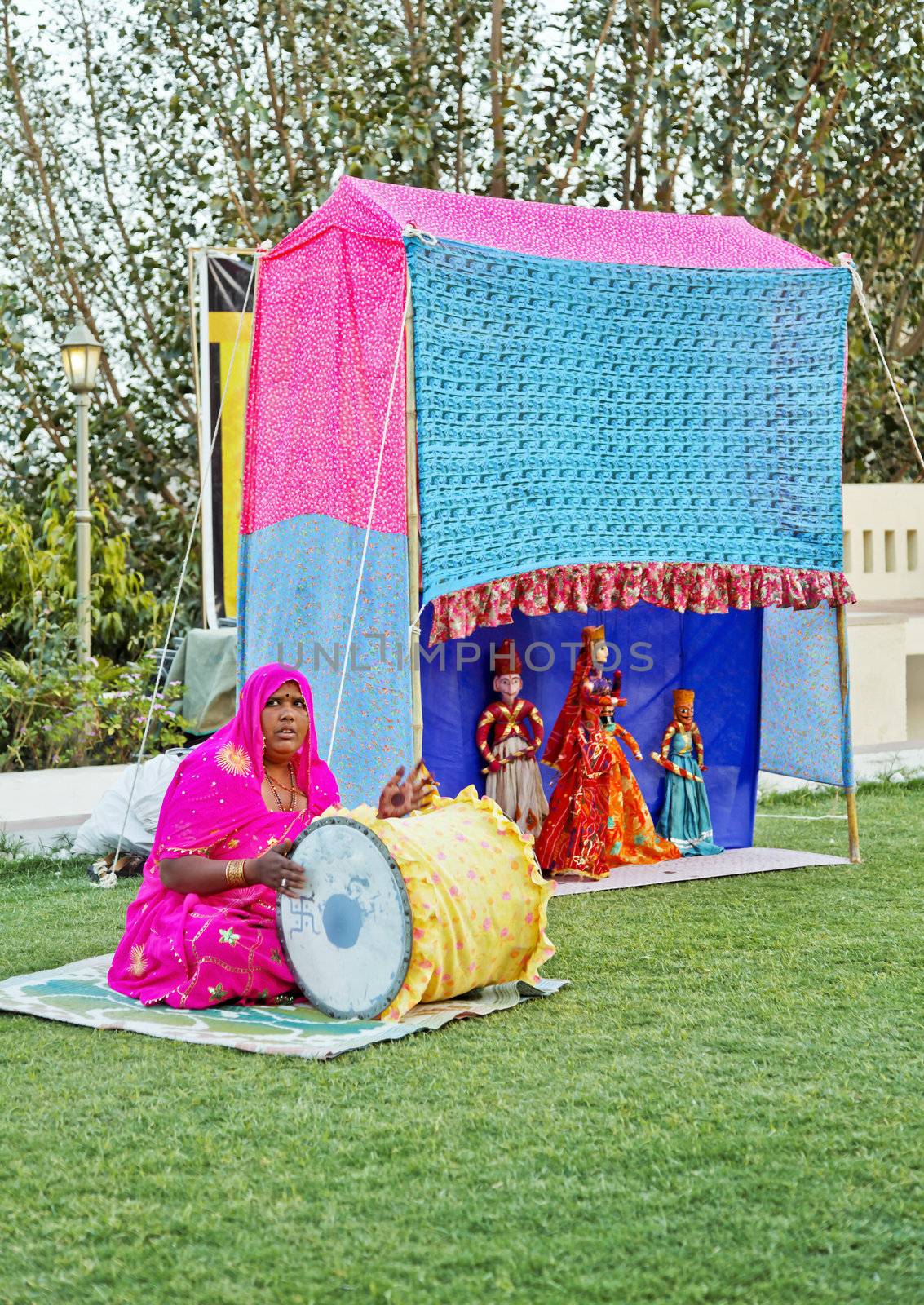 Portrait of an early evening outdoor performance on a lawn by traveling troupe man and wife team of Rajasthani puppeteers in India