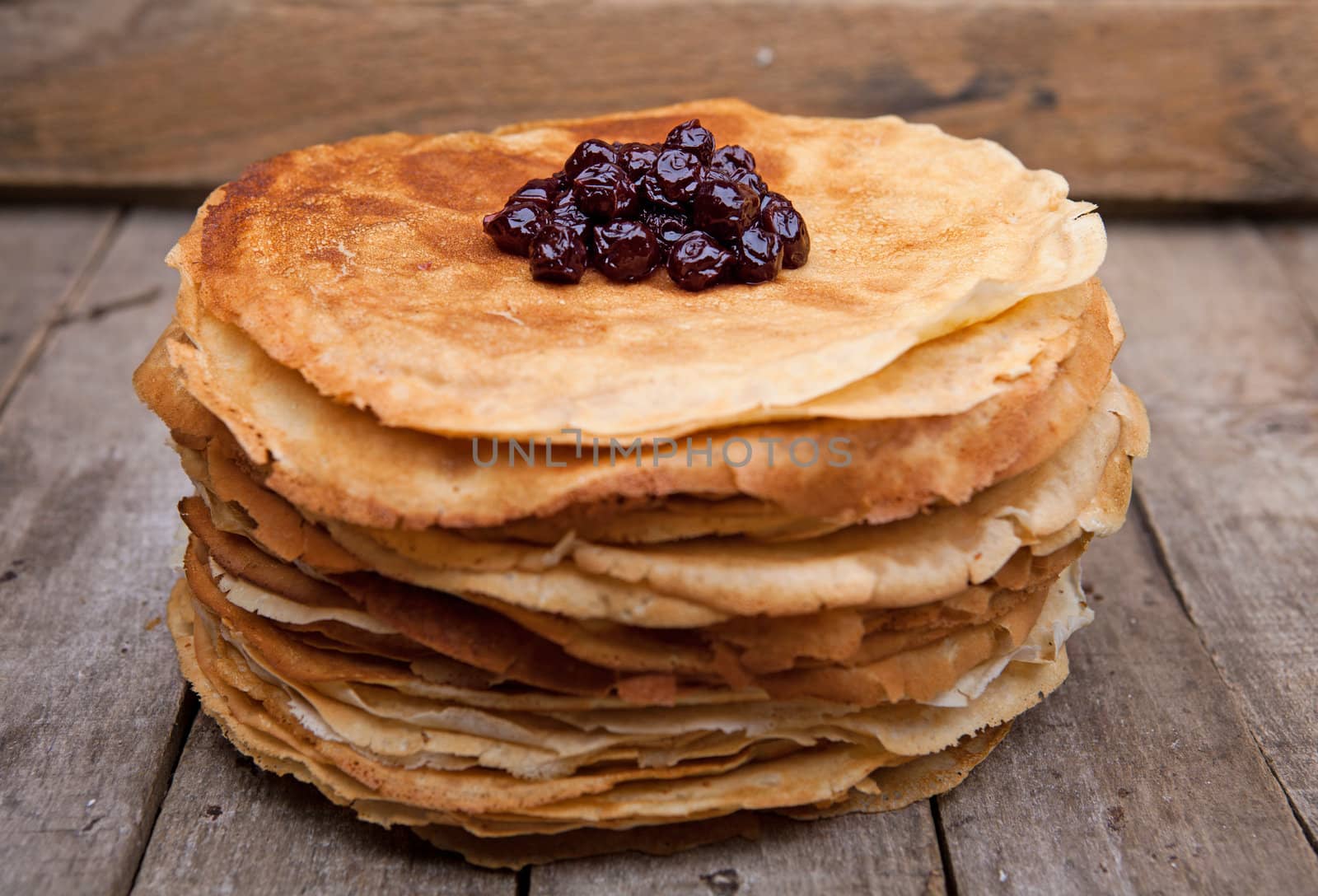 Crepes on the wooden table with cherry