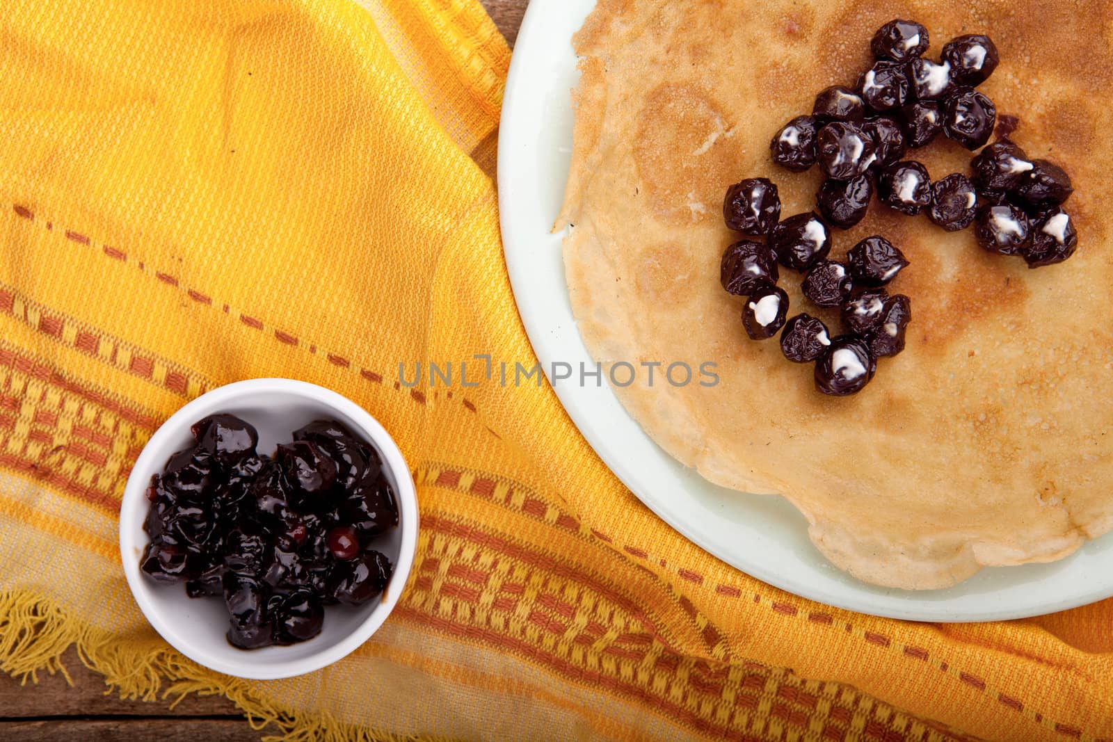 Crepes on the tablecloth with cherry and with sour cream