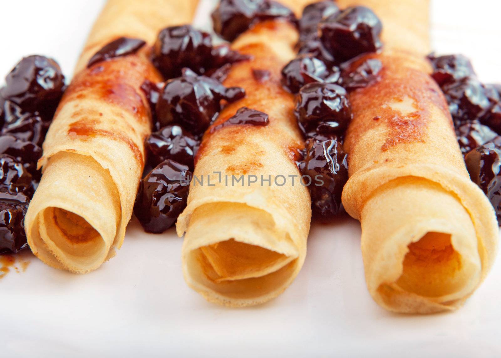 Crepes on white plate with cherry